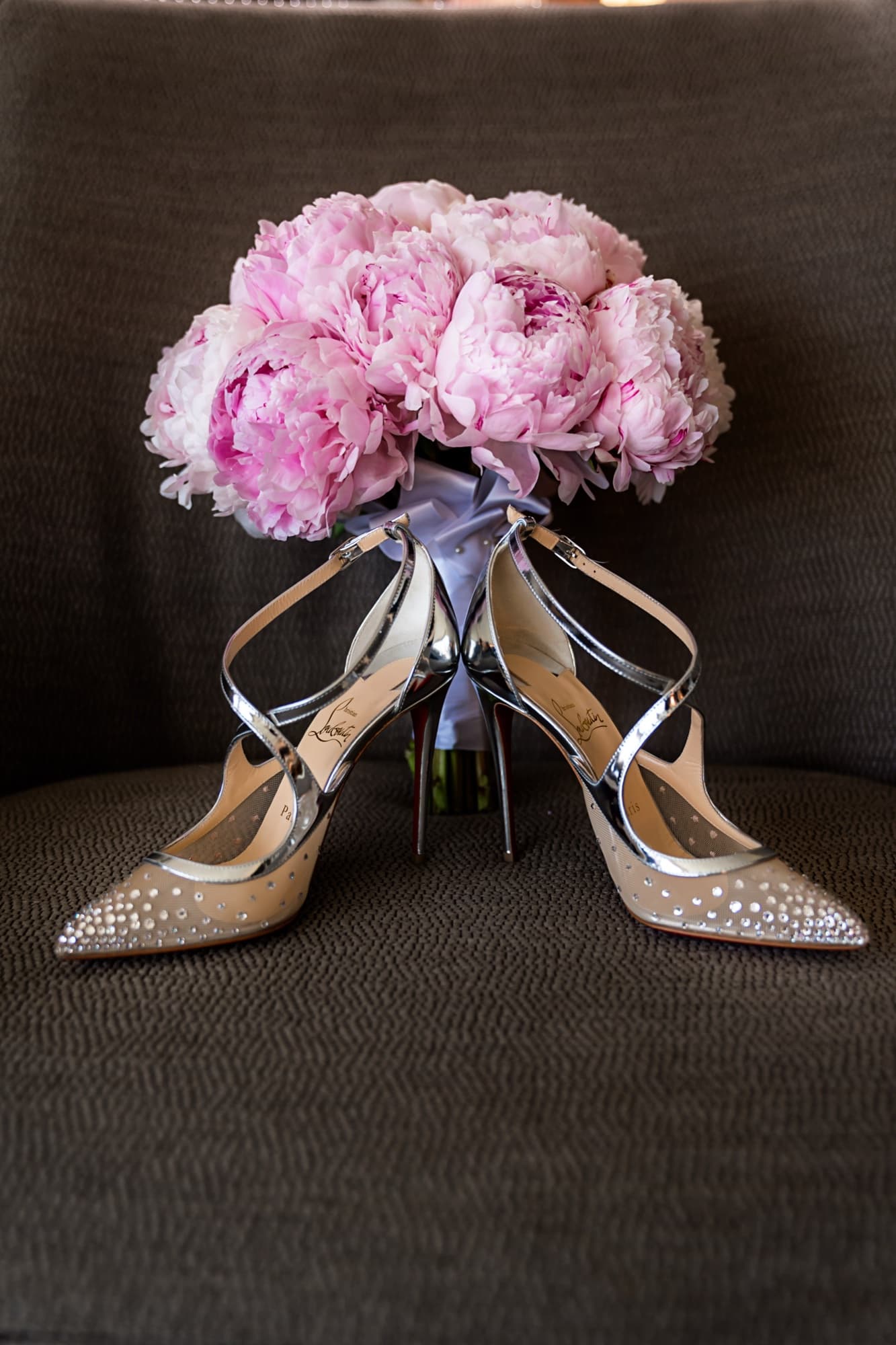 Blush peony bouquet resting on crystal-embellished bridal heels before the wedding