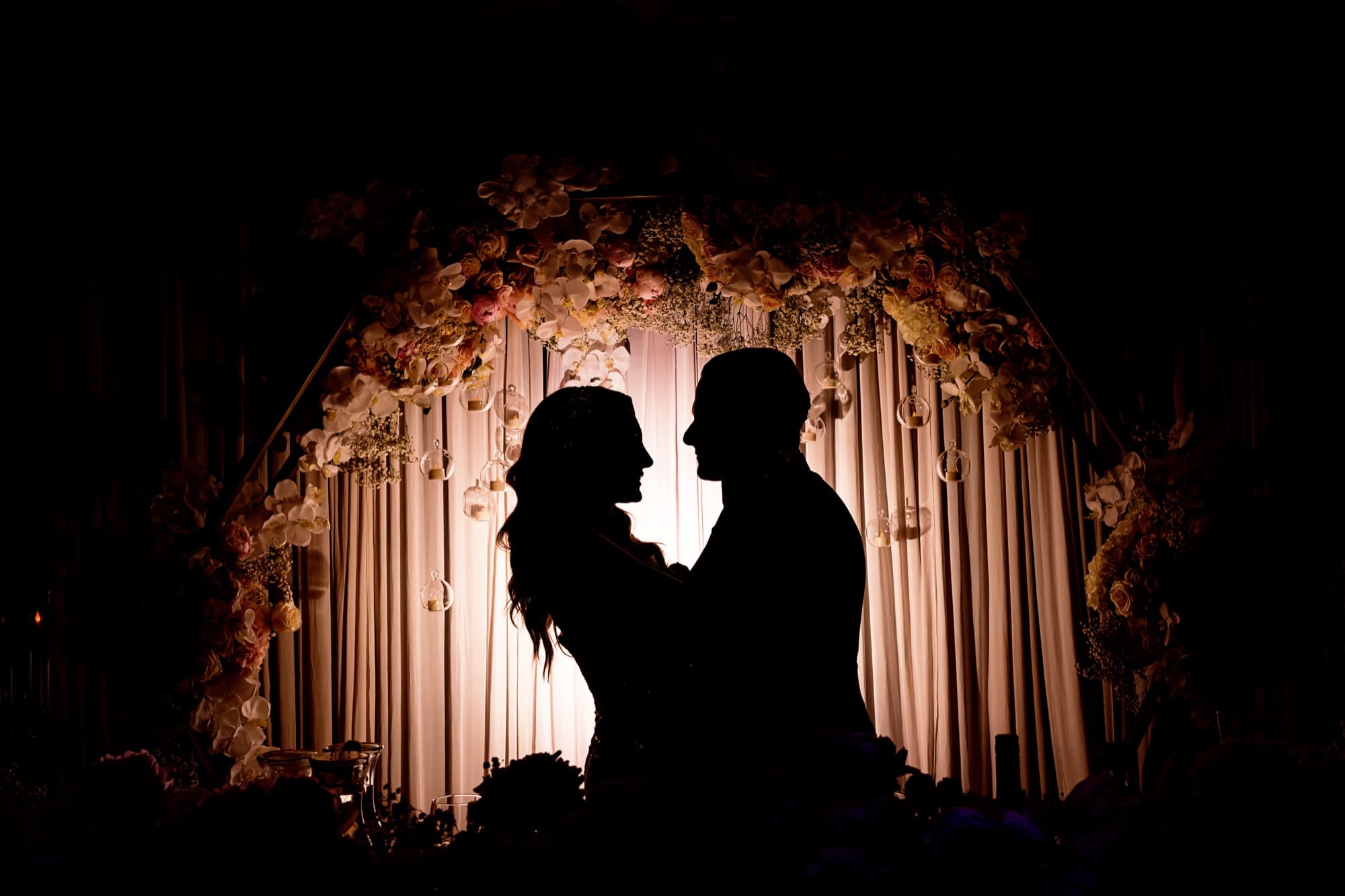 Backlit silhouette of Laura and Garen inside the floral arch at their Vertigo Event Venue reception