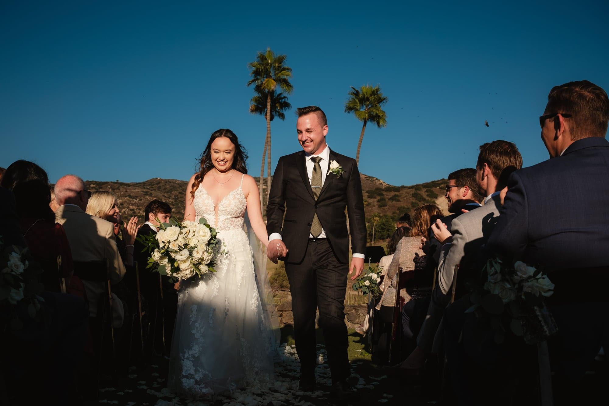 Leslie and Paul leaving the ceremony together as guests celebrate