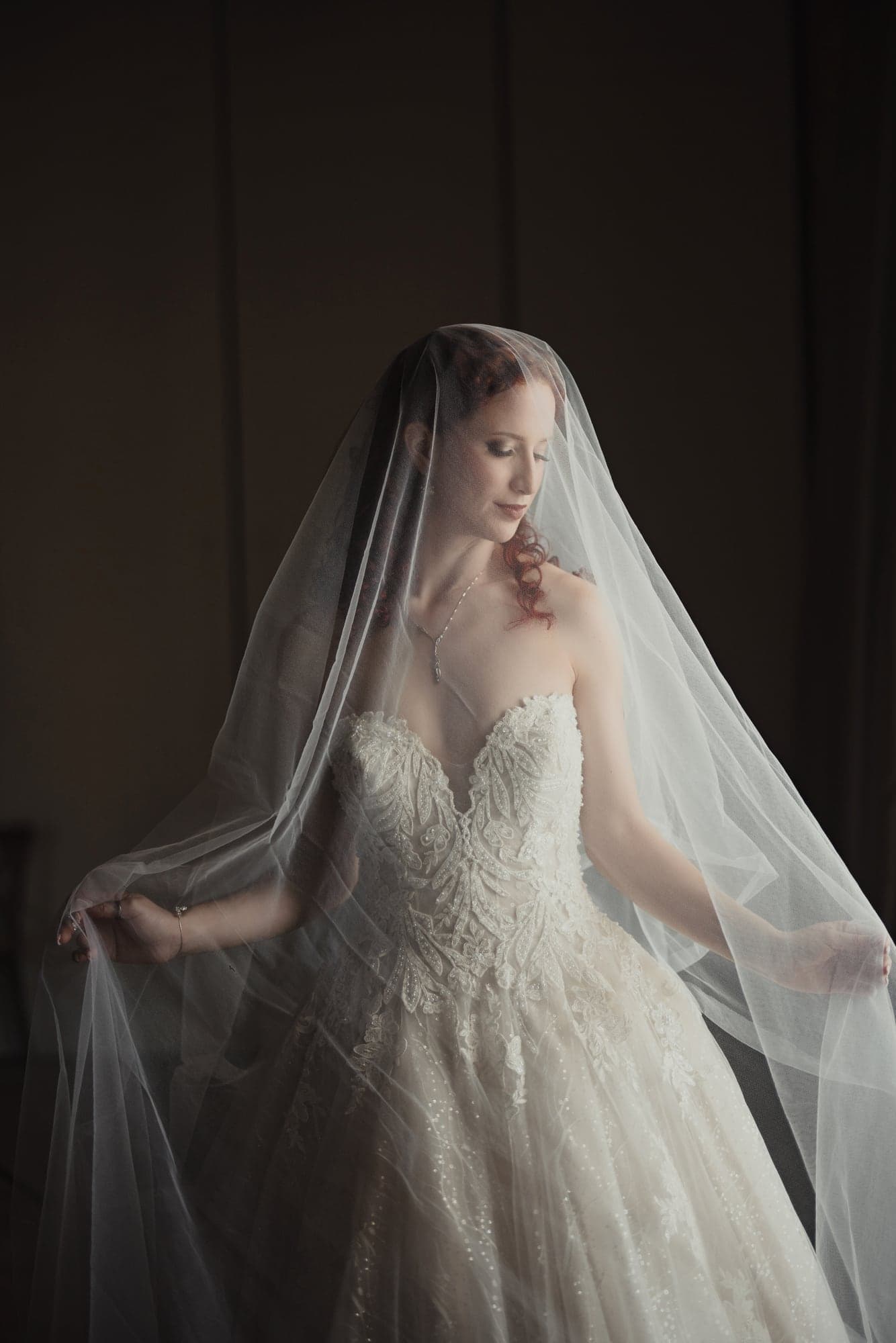 Maria in window light wearing her wedding veil