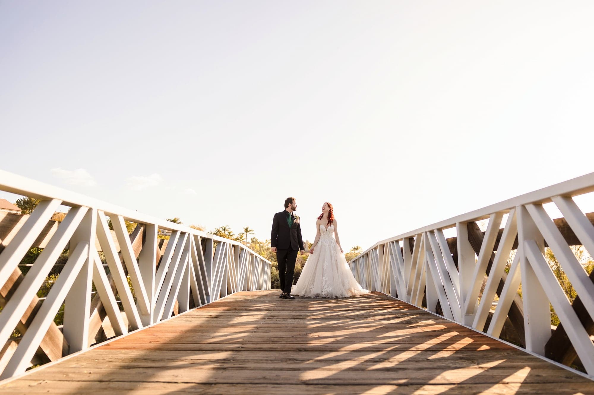 Maria and John walking across a bridge in evening light after their wedding