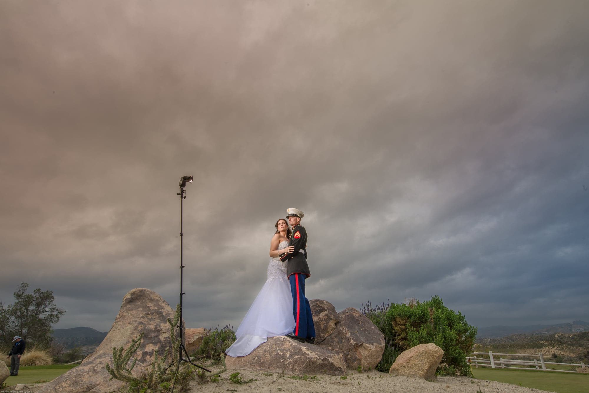 Gootman couple embracing beneath dramatic clouds