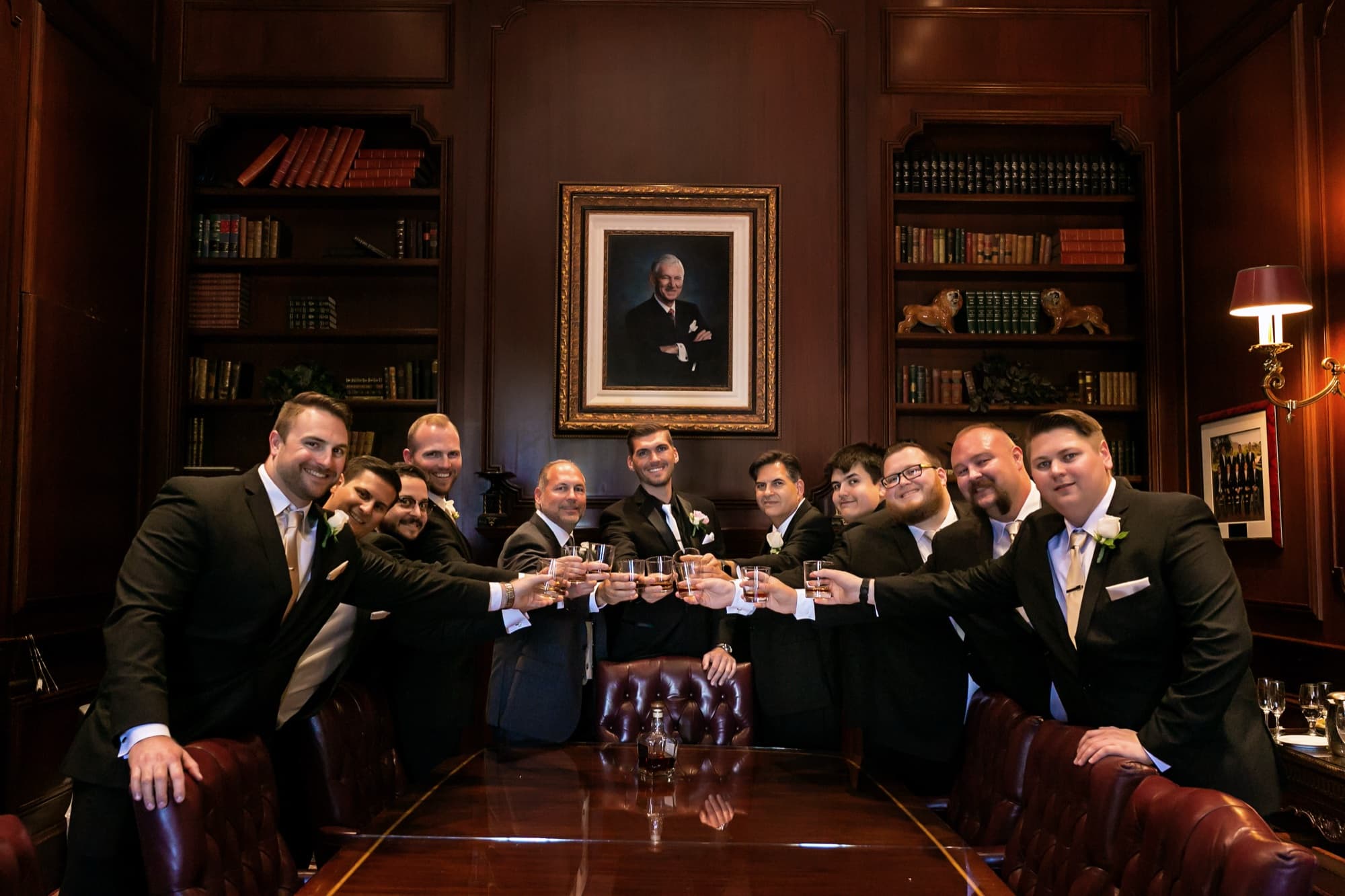 Brandon and his groomsmen raising a whiskey toast around the leather table in the wood-paneled Sherwood club library