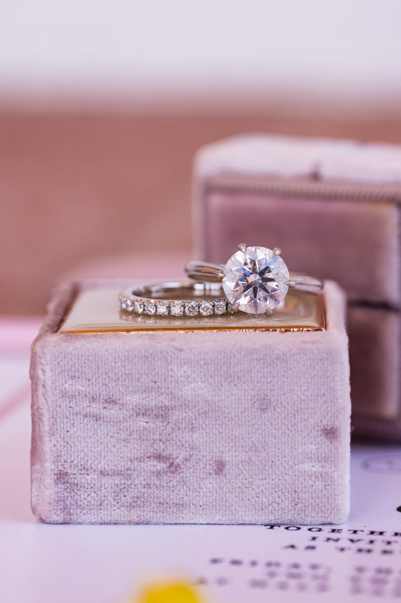 Round brilliant solitaire engagement ring and pave wedding band stacked on a blush velvet ring box at a Sherwood Country Club wedding