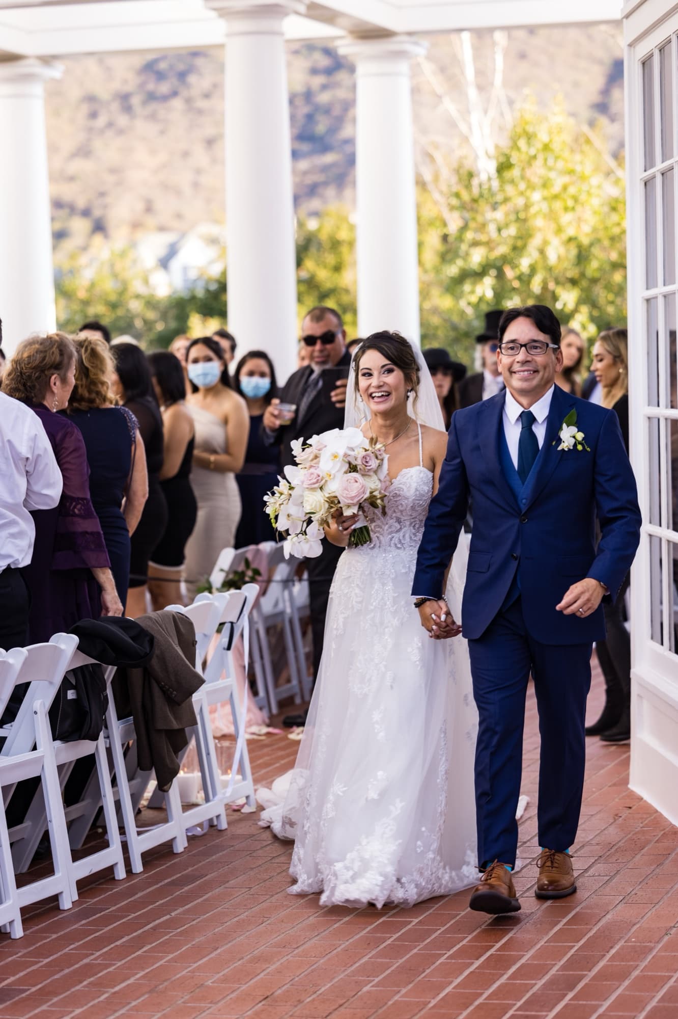 Bride laughing and holding the groom's hand as they walk back up the petal-lined aisle after their Sherwood Country Club wedding ceremony