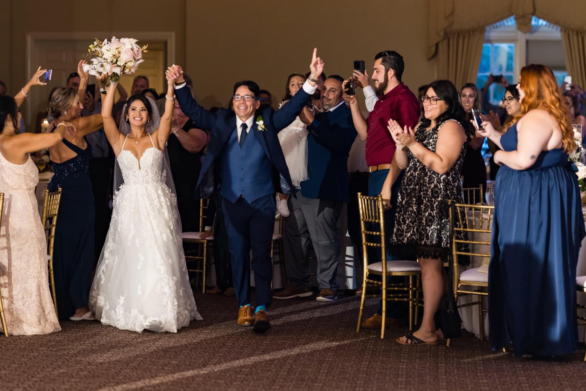 Bride and groom cheering during their grand entrance into the Sherwood Country Club ballroom while guests applaud