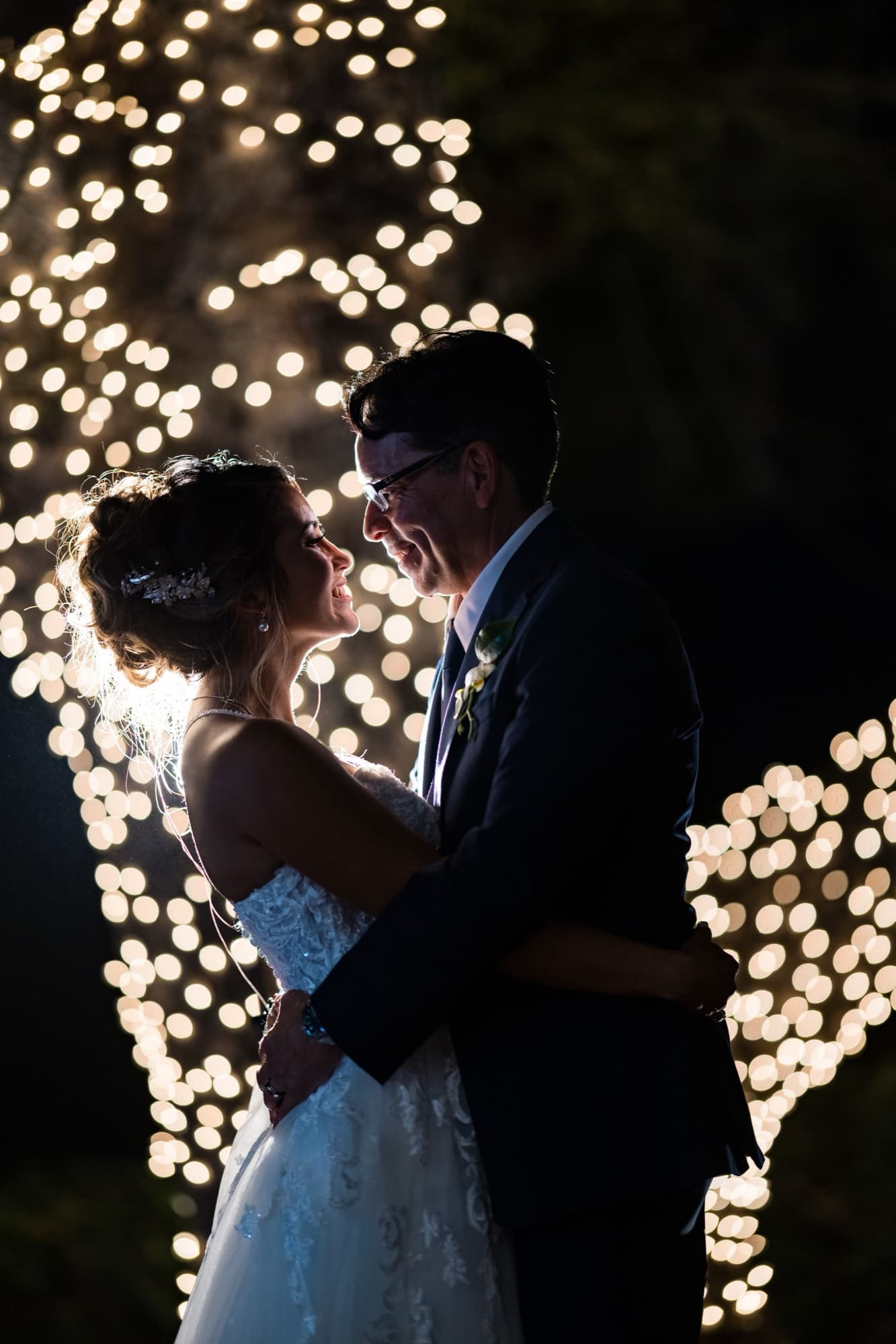 Bride and groom embracing at night in front of a wall of string lights at Sherwood Country Club, photographed by Michael Anthony Photography