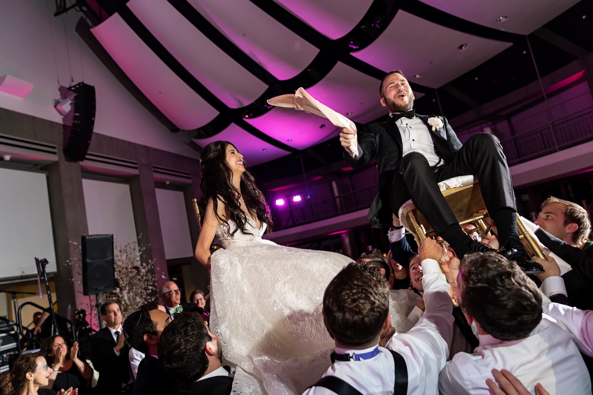 Jeff lifted on a chair above the crowd during the hora as Rachel is raised beside him at the Skirball reception