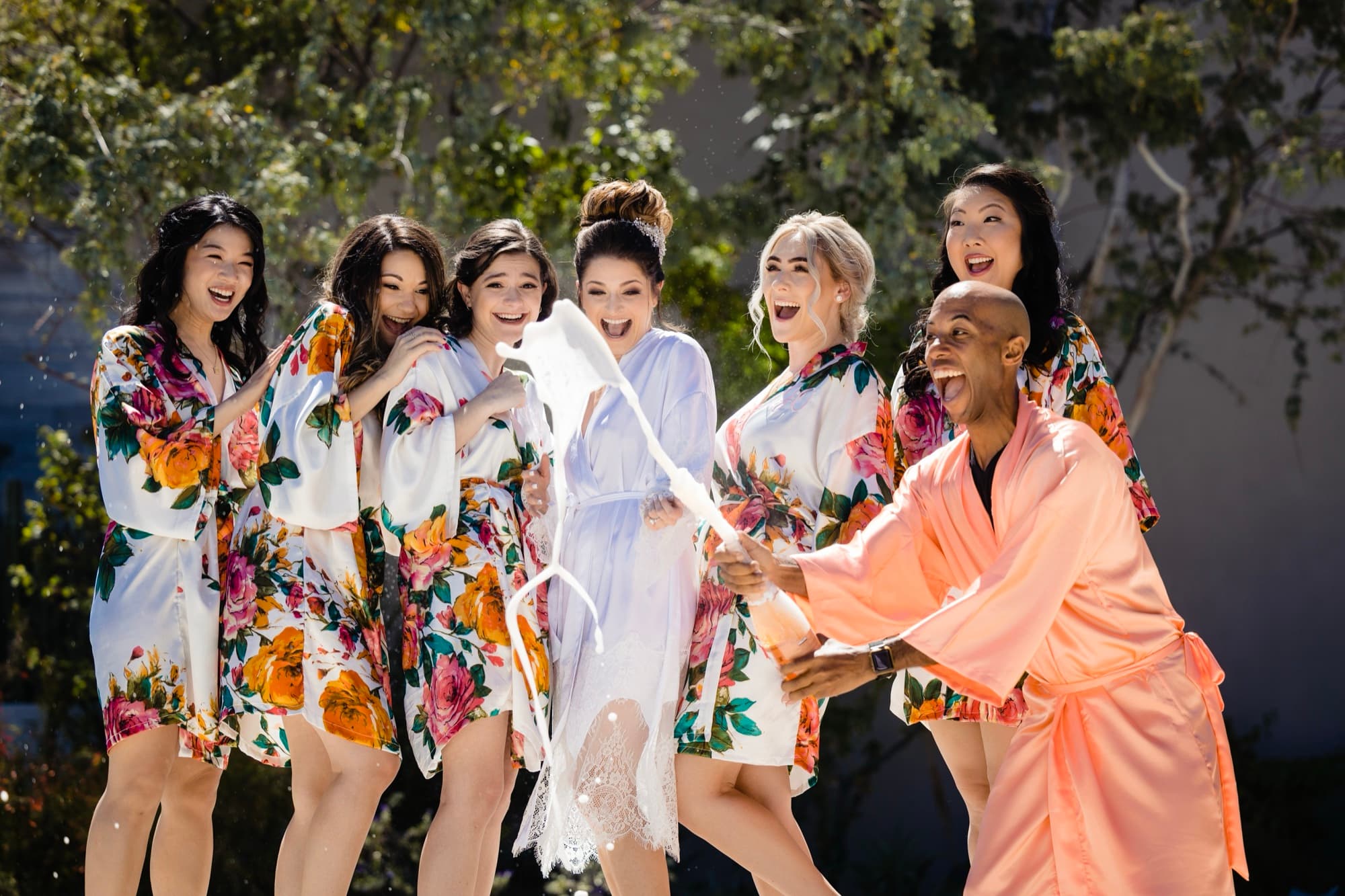 Yana's bridal party in vivid floral robes cheering around her during prep at Solaz Los Cabos