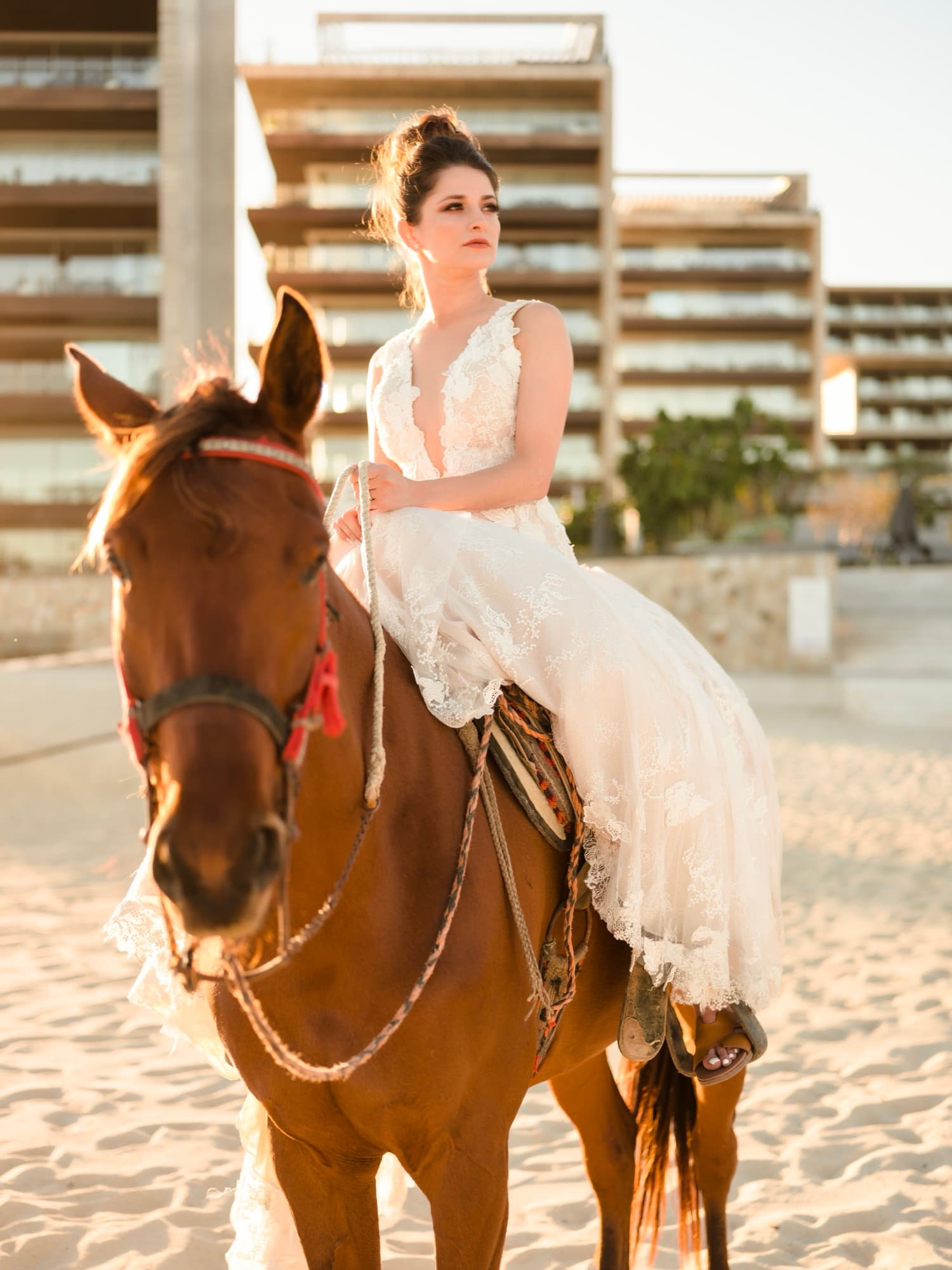 Yana in her lace gown riding a horse down the beach at Solaz Los Cabos