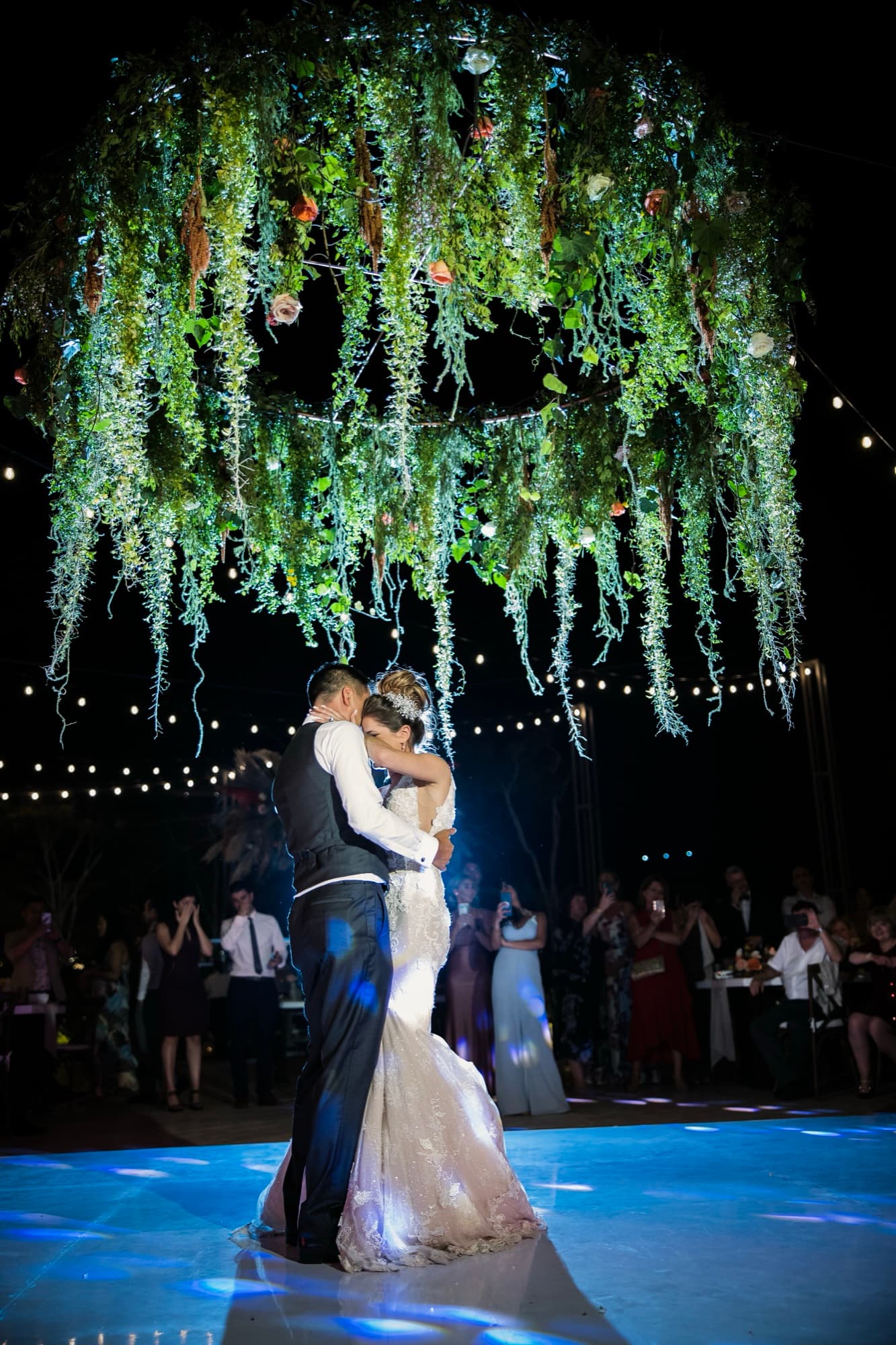 Yana and Jonathan dancing at night beneath the hanging greenery and lights over the Solaz dance floor