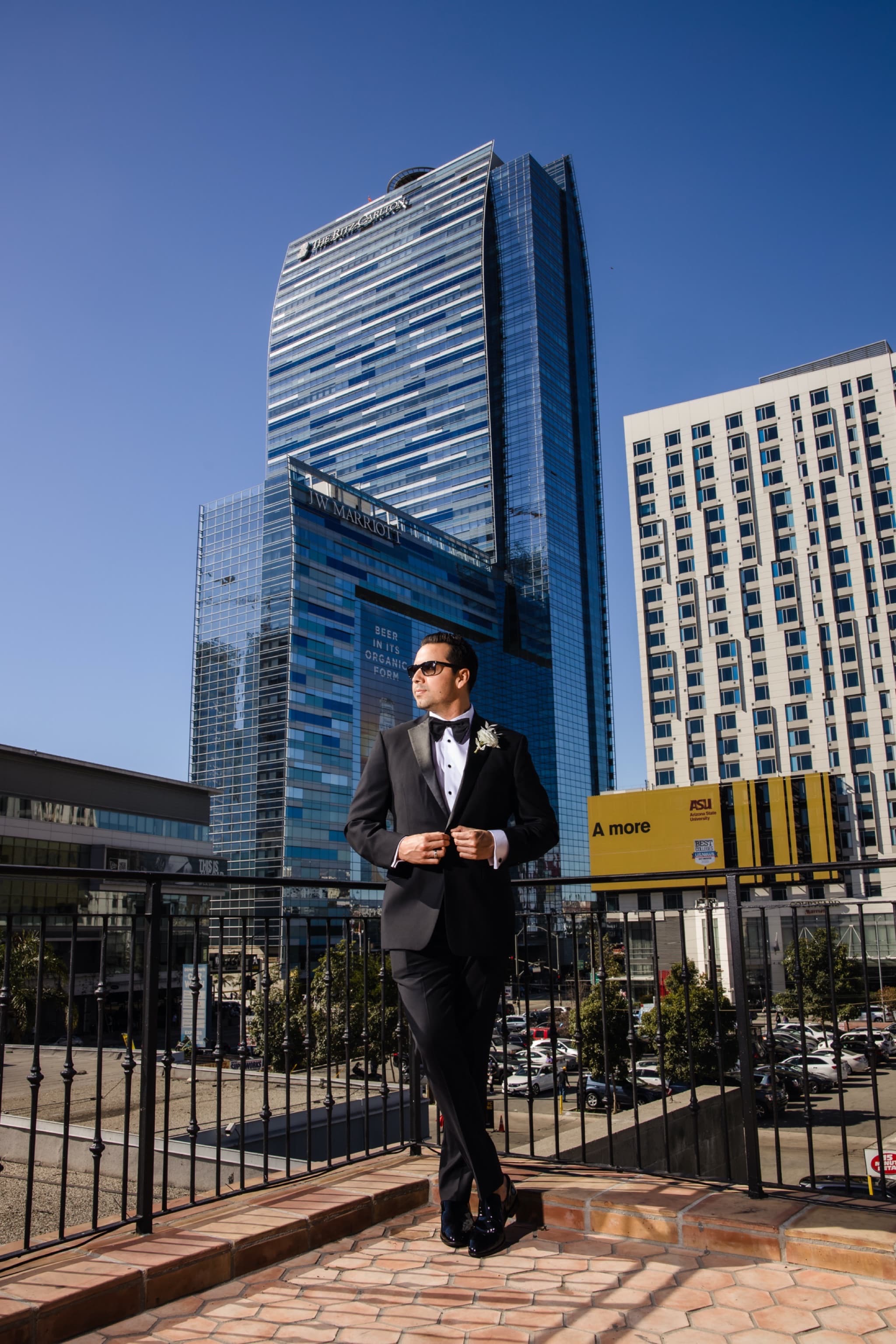 Ryan in his tuxedo and sunglasses standing before the downtown Los Angeles towers