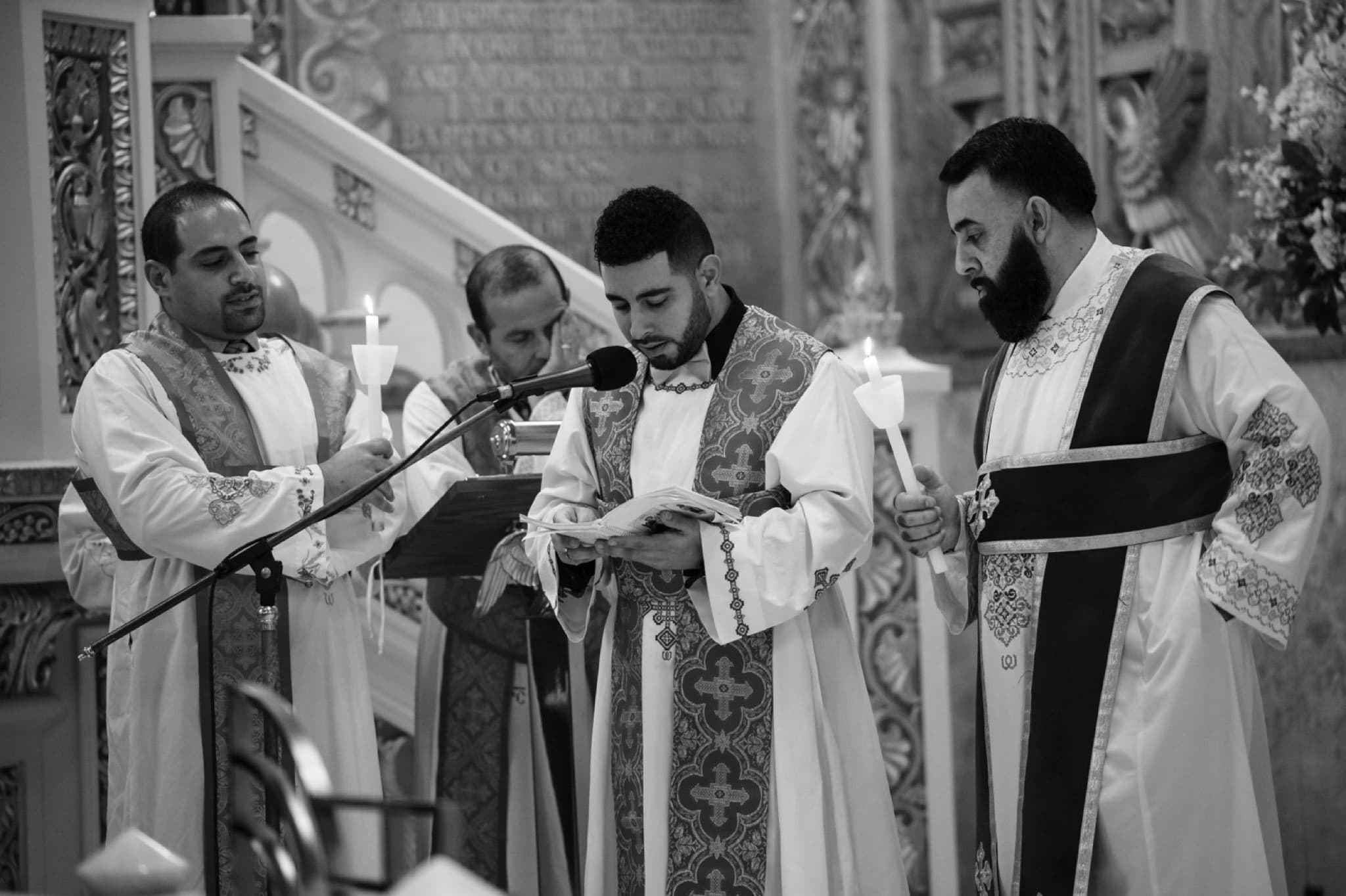 Orthodox clergy chanting by candlelight during the ceremony at St. Sophia Cathedral