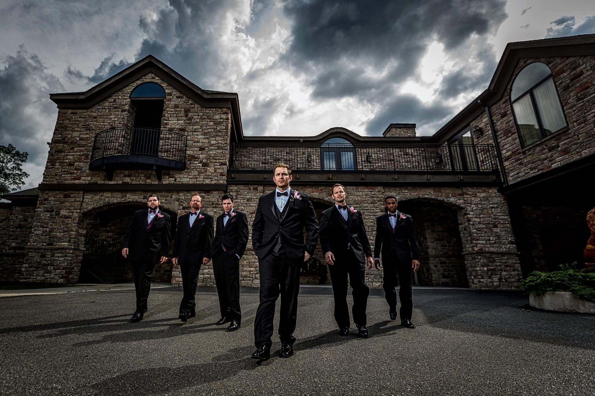 The groom and groomsmen outside the stone inn