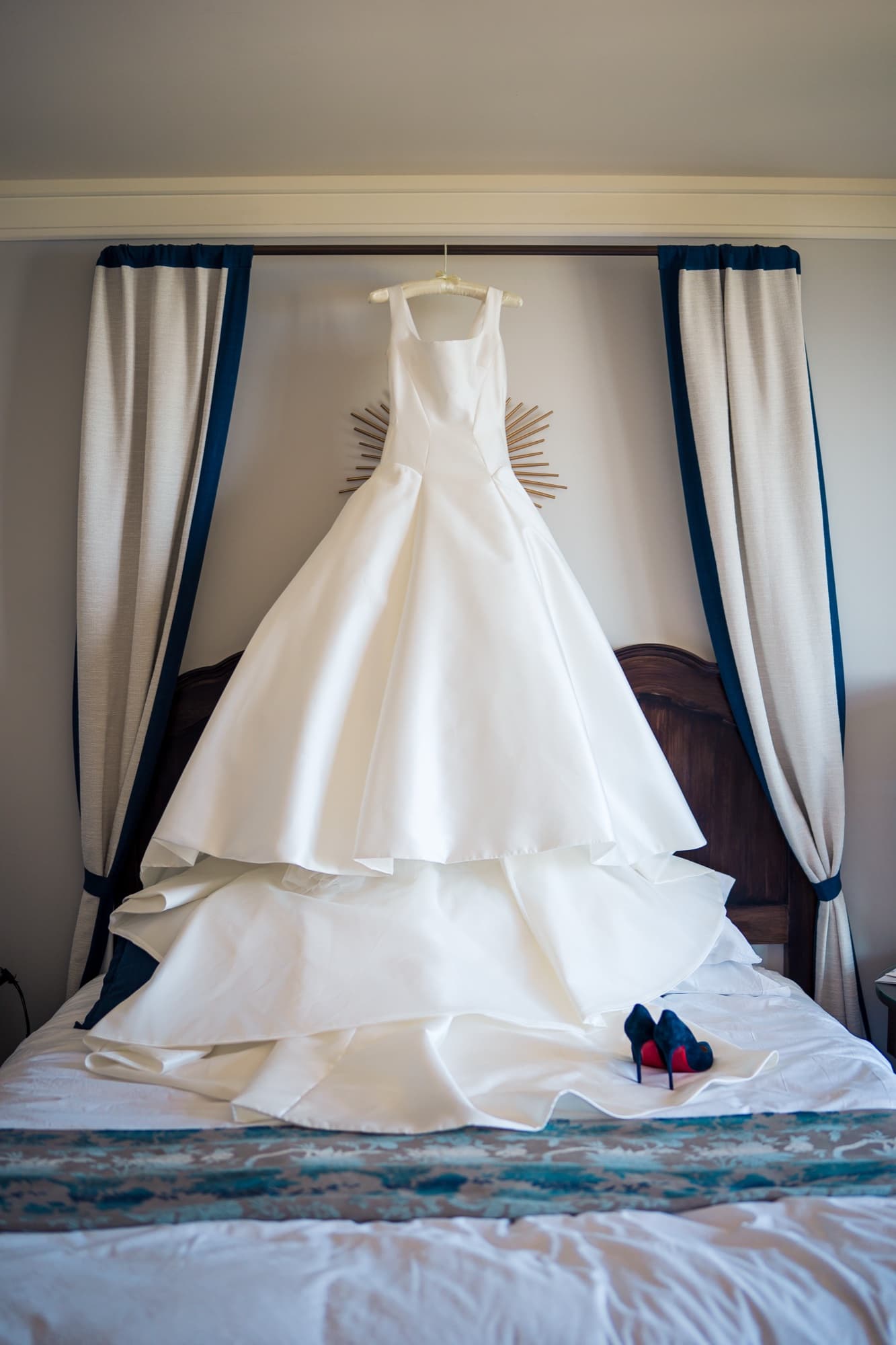 Elise's tiered ballgown hanging over the four-poster canopy bed in the Terranea suite with her blue heels on the bed