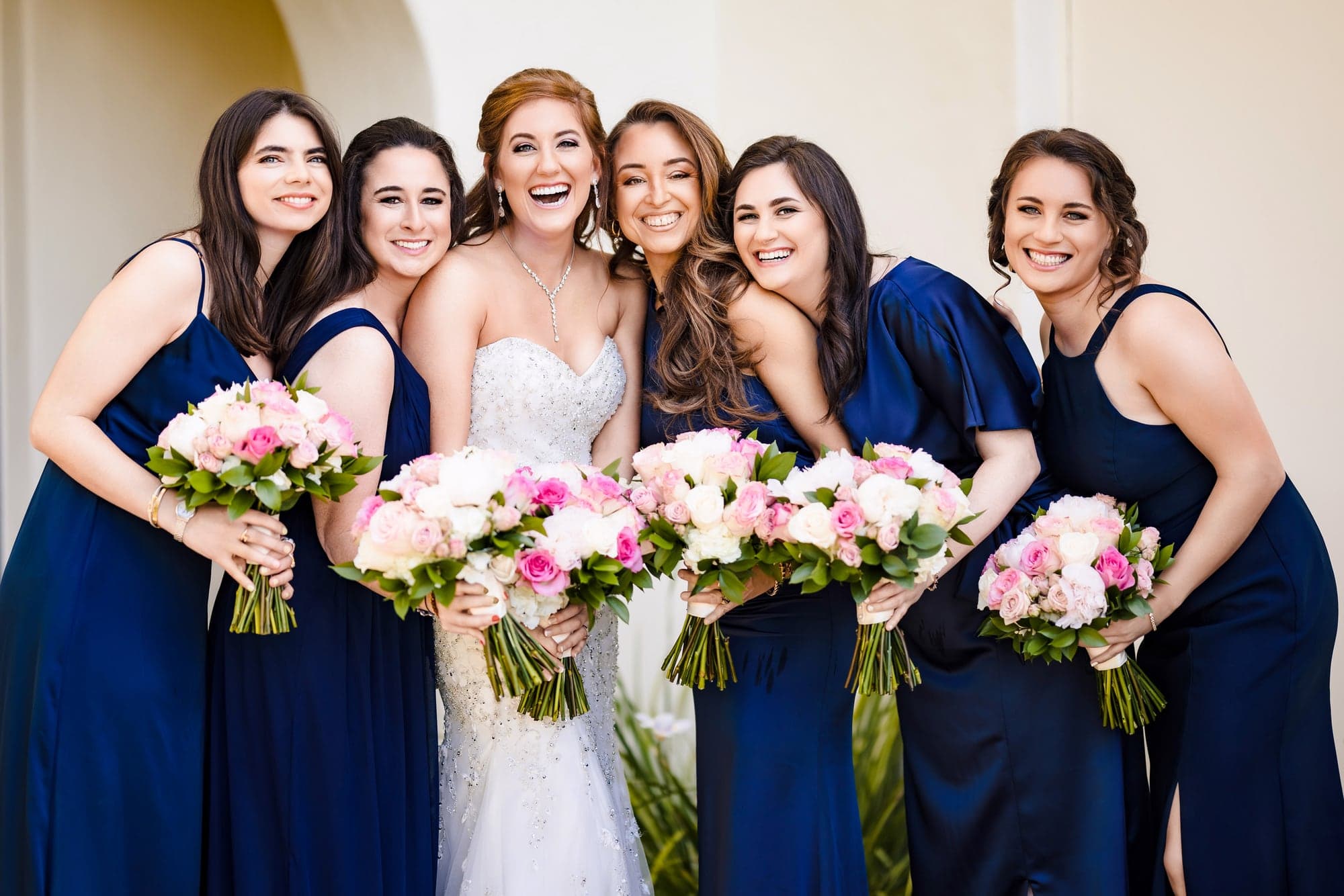 Sarah with her wedding party in navy dresses and pink florals at Terranea Resort