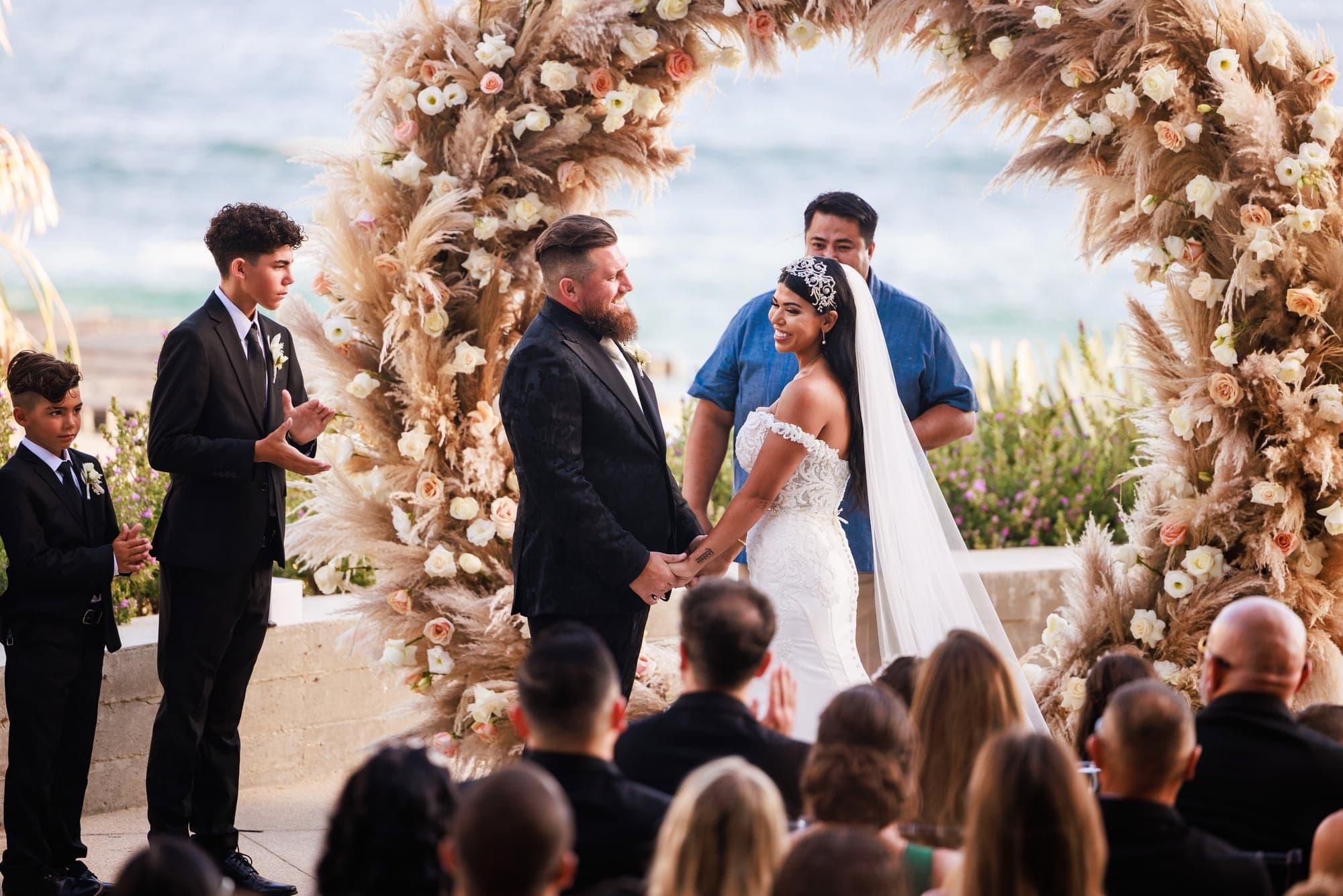 Bryanna and Justin exchanging vows inside the circular floral arch overlooking the ocean