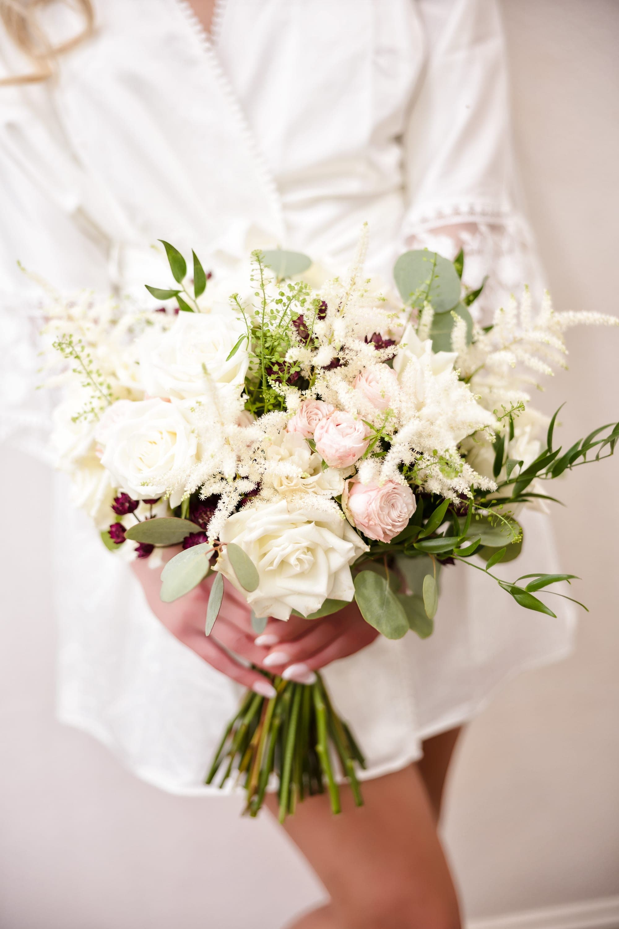The bridal bouquet of white and blush blooms with deep burgundy accents