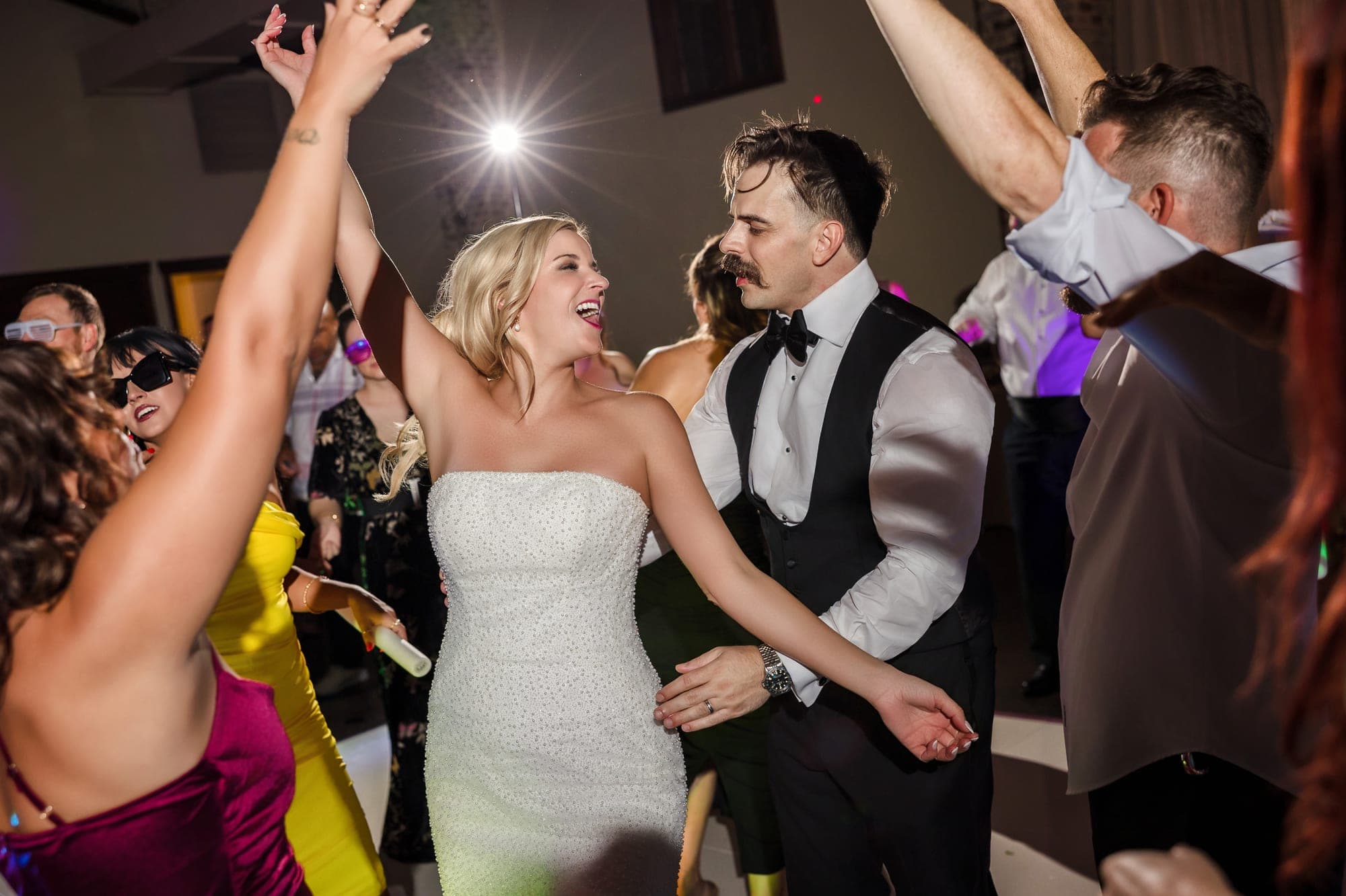 A packed dance floor with Beth and Austin in the middle, hands in the air