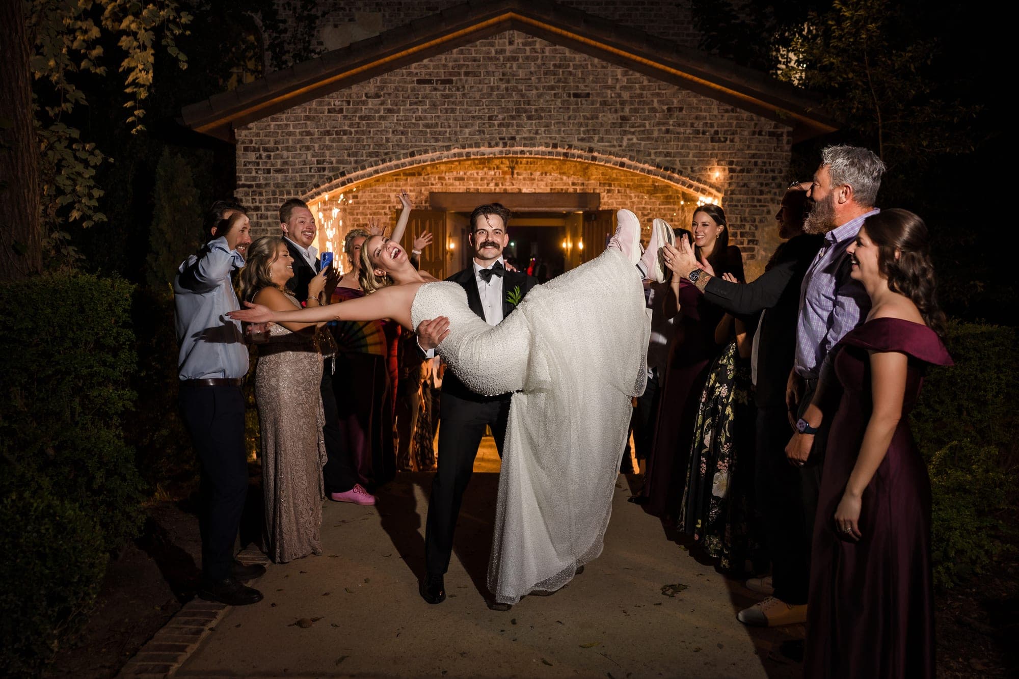 Austin dipping Beth in the lit brick archway as guests cheer them out