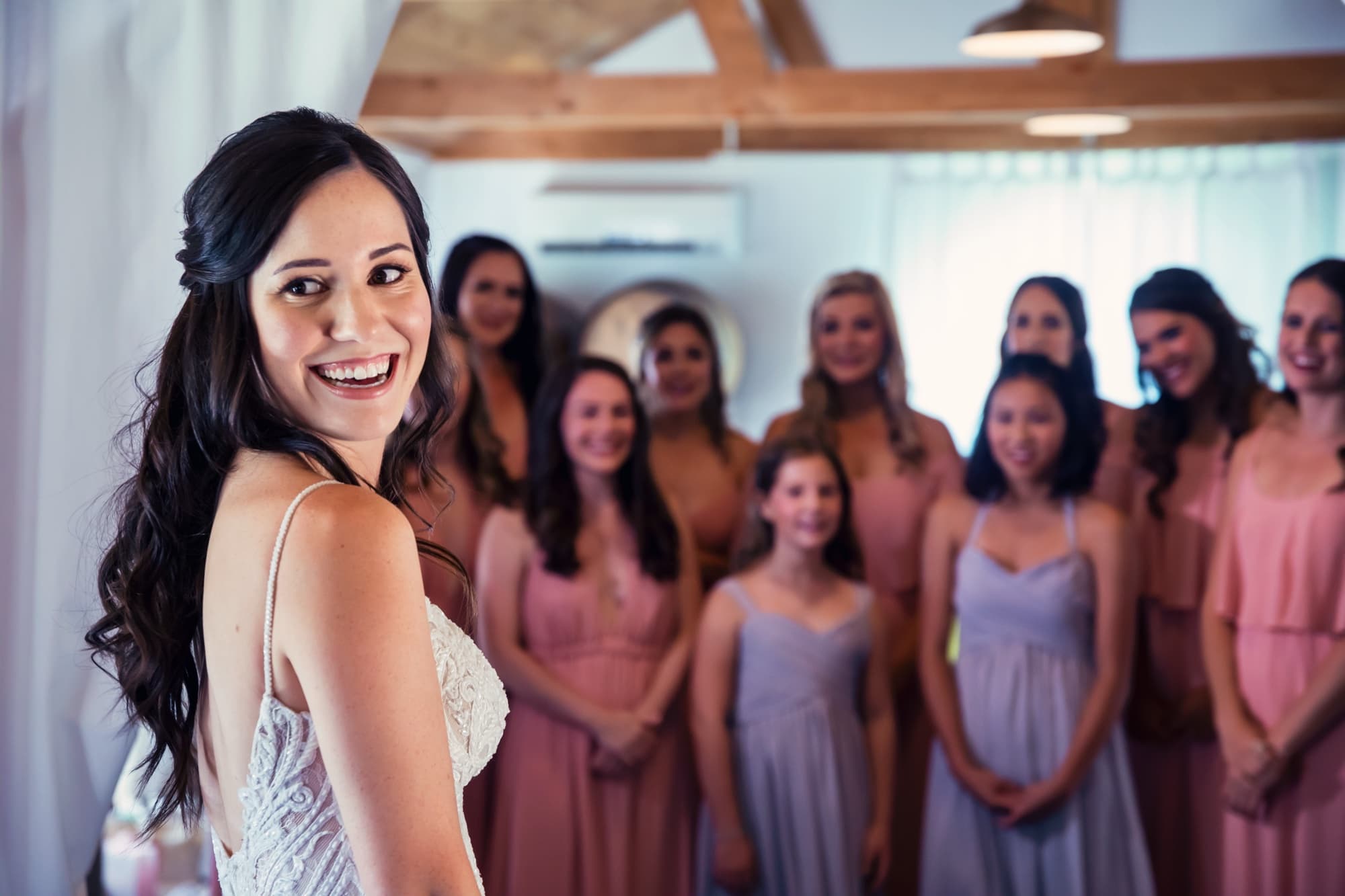 Allison laughing over her shoulder with her bridesmaids gathered behind her in the barn