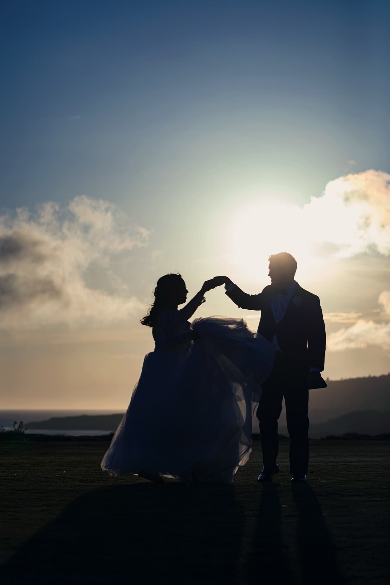 Silhouette of Jamie twirling under James's hand against the setting sun on the bluffs at Trump National