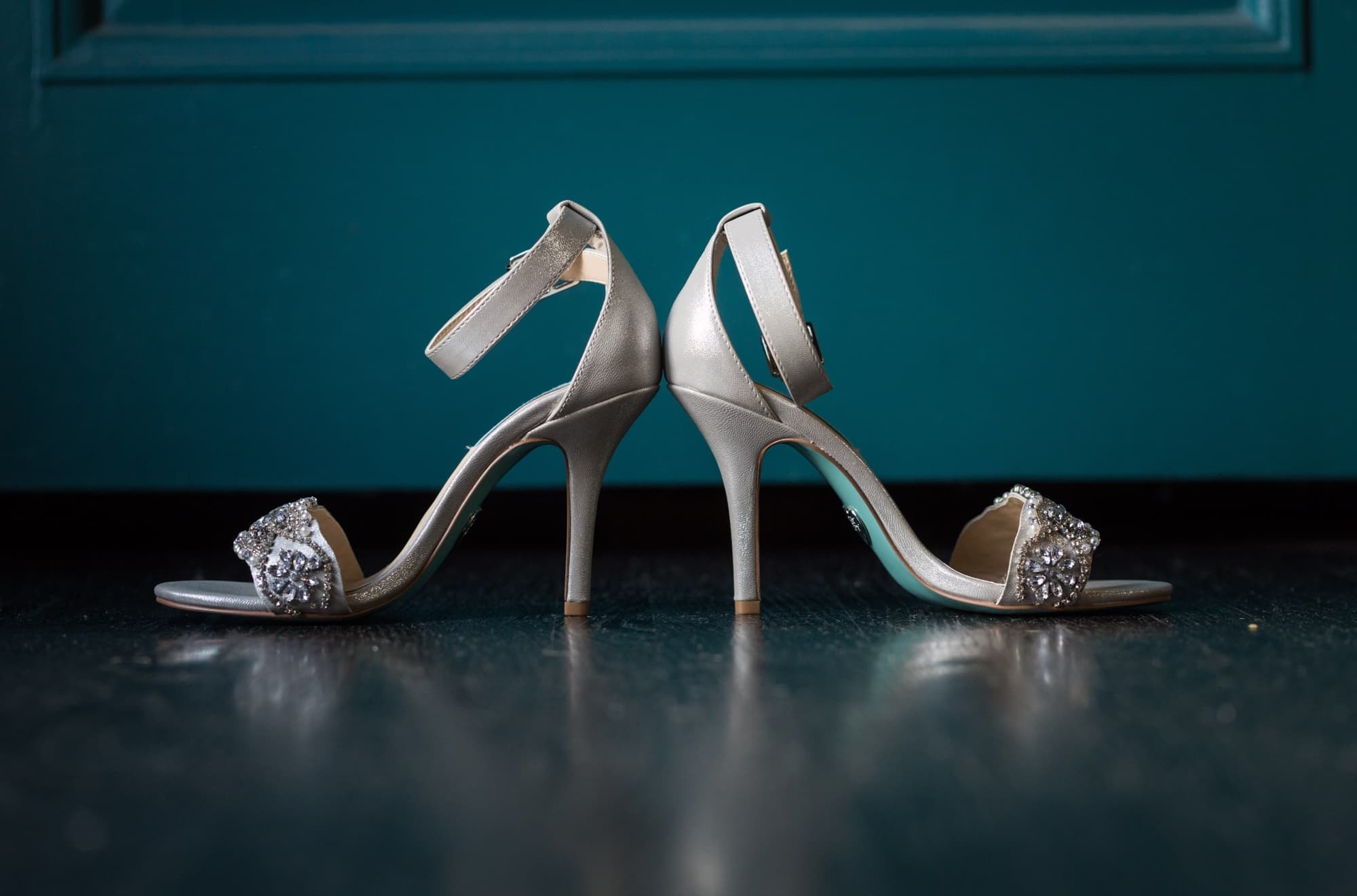 Jeweled silver bridal heels standing toe to toe against Vibiana's signature teal door and dark floor