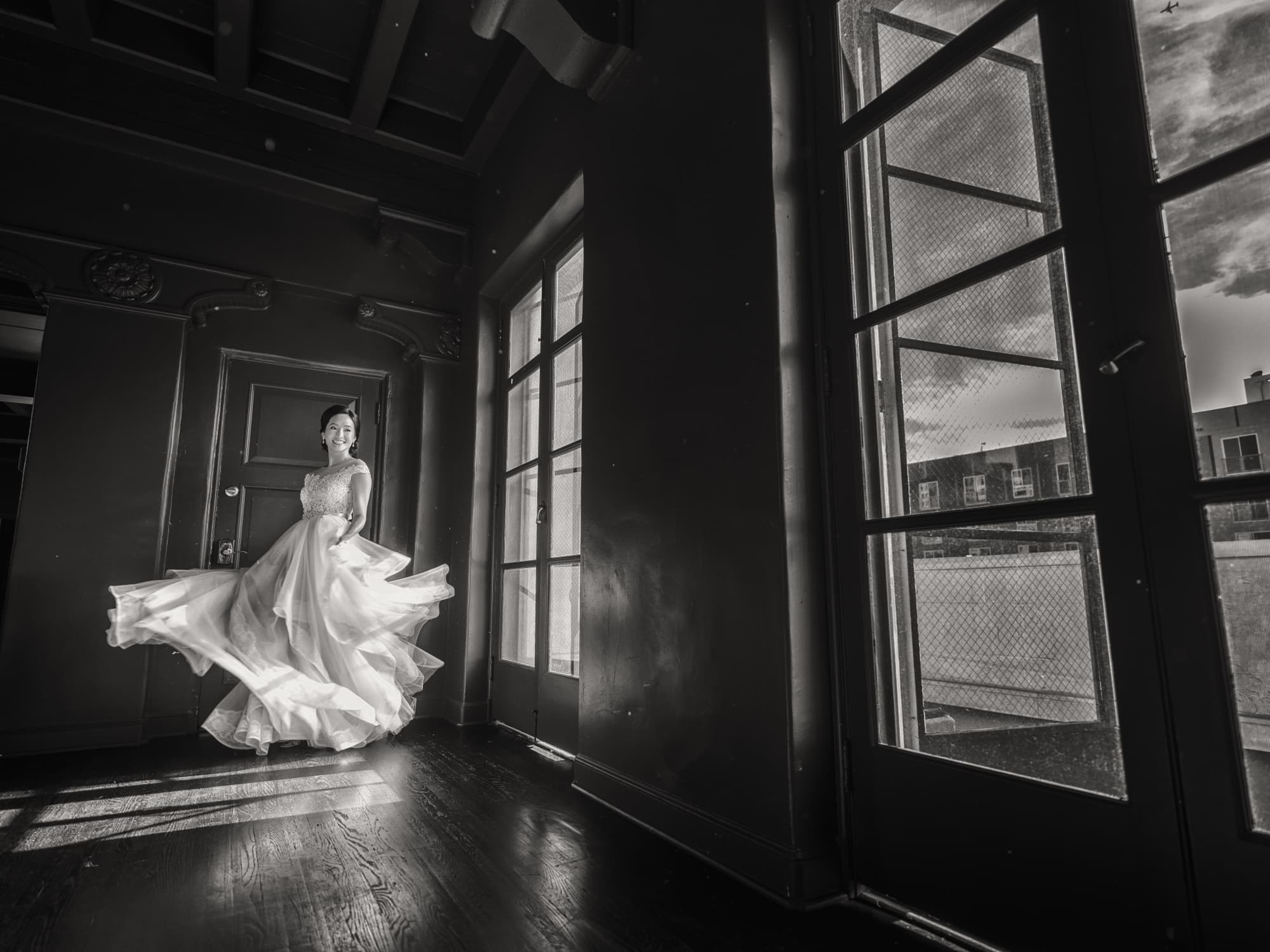 Black and white photograph of the bride spinning her tulle gown in the dark-paneled suite at Vibiana in downtown Los Angeles