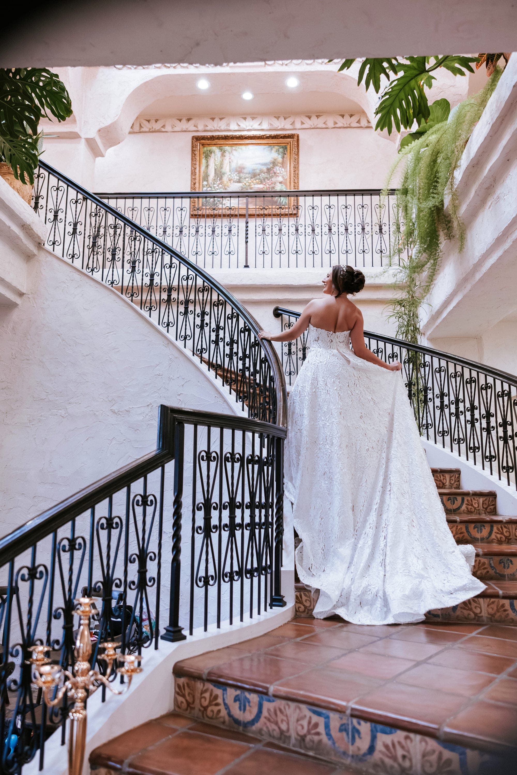 Kelsey climbing the villa's grand iron staircase, her train trailing over the Spanish tile