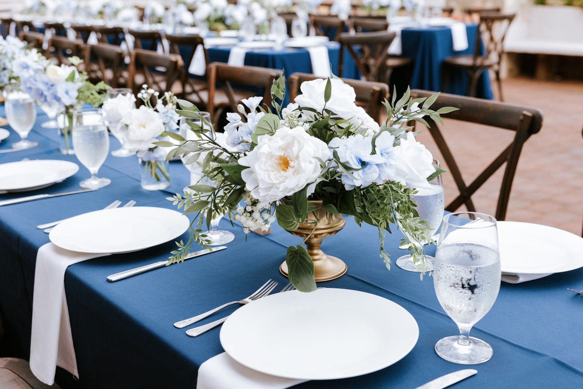Feasting tables on the terrace in navy linen with gold compotes of white and blue florals