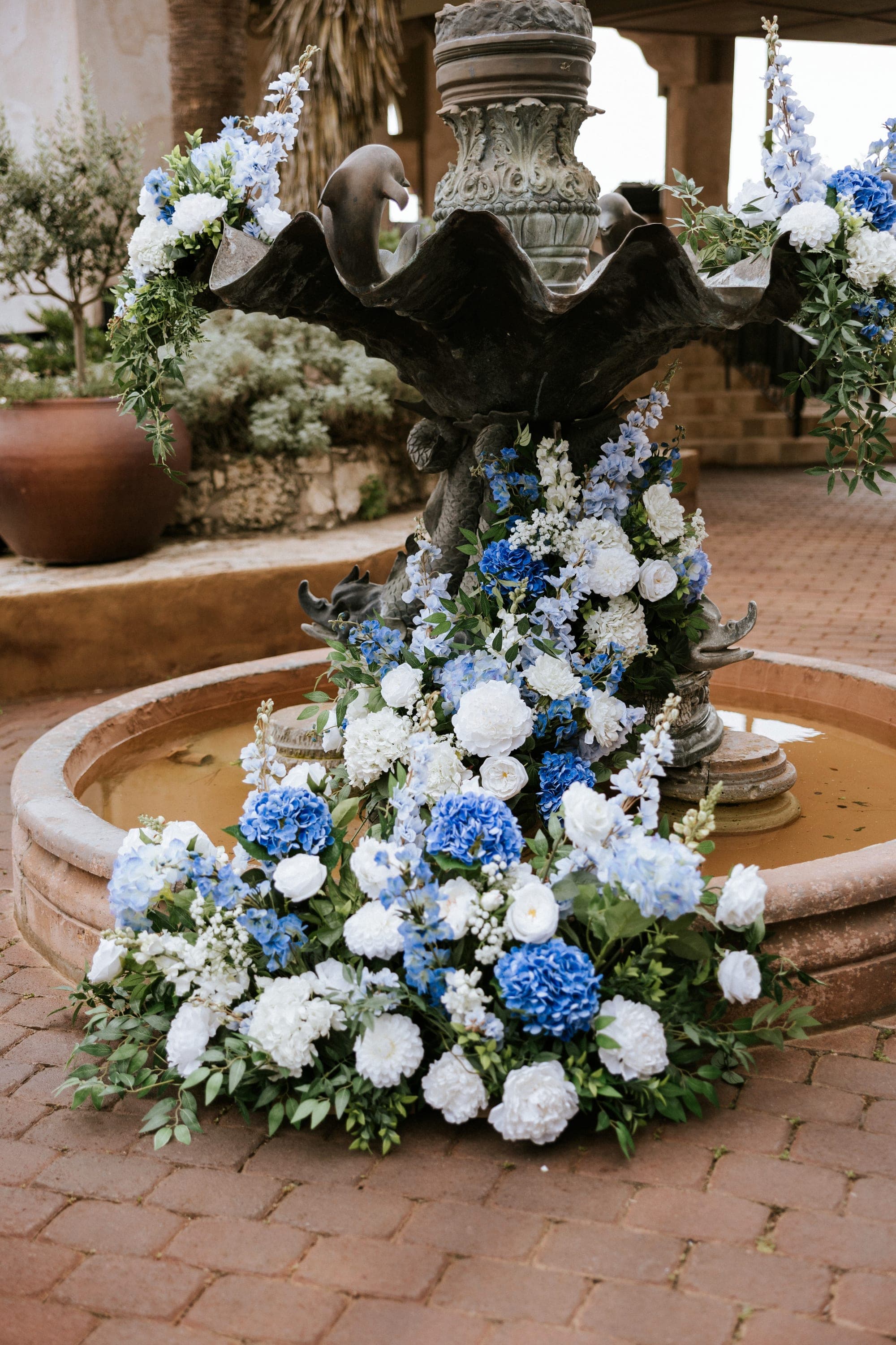 The villa's courtyard fountain banked in blue and white hydrangea and roses