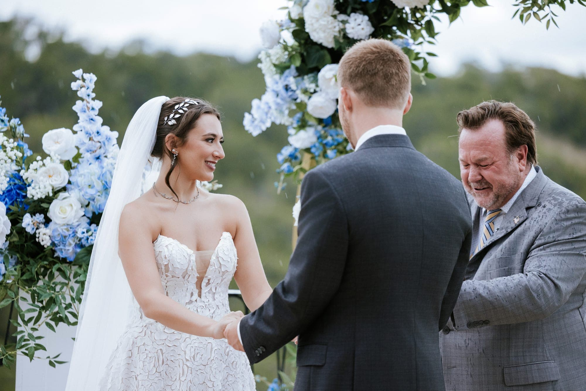 Kelsey beaming at Eric as the officiant breaks up laughing