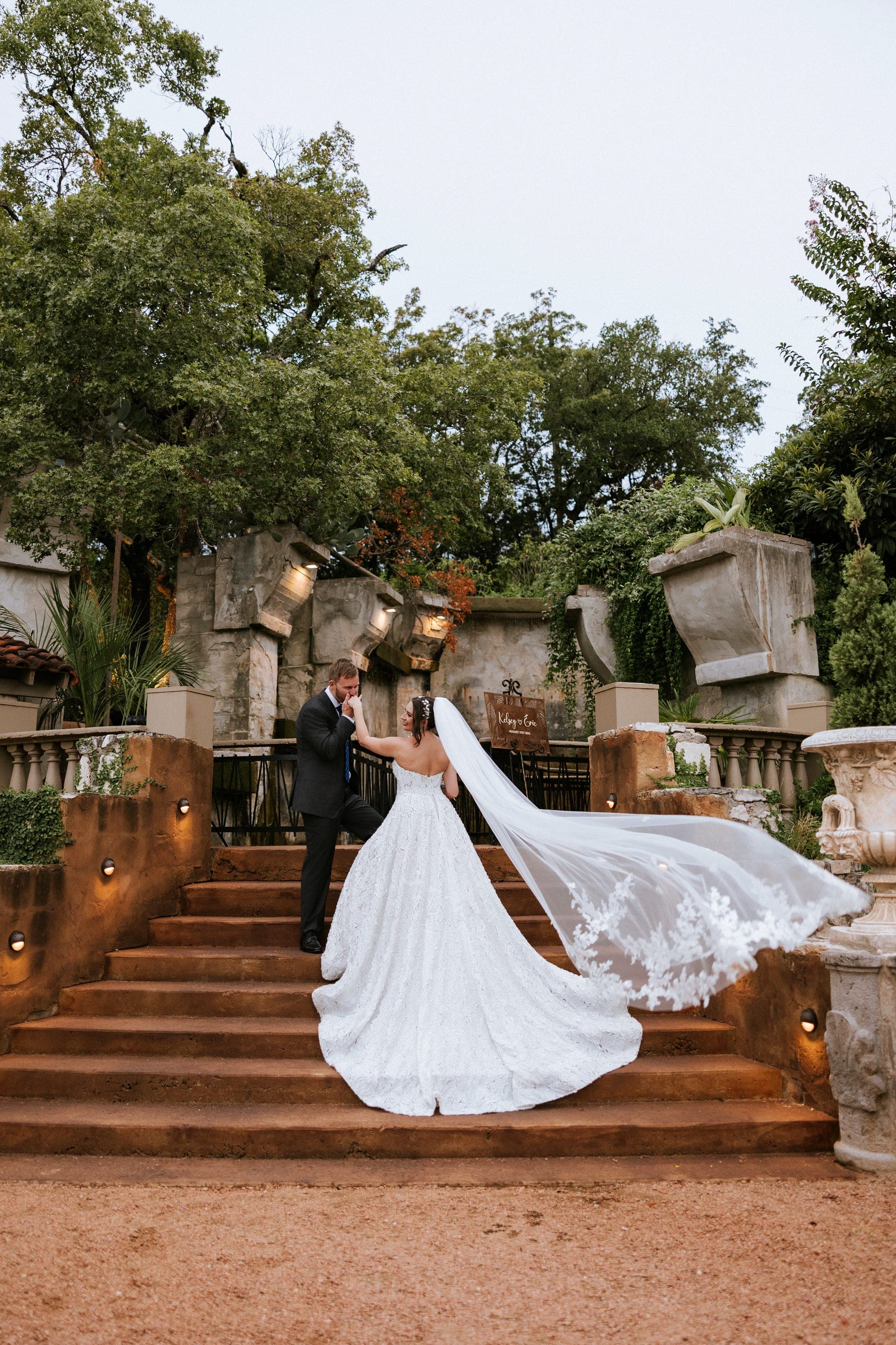 Eric leading Kelsey down the garden steps, her lace-edged veil flowing behind