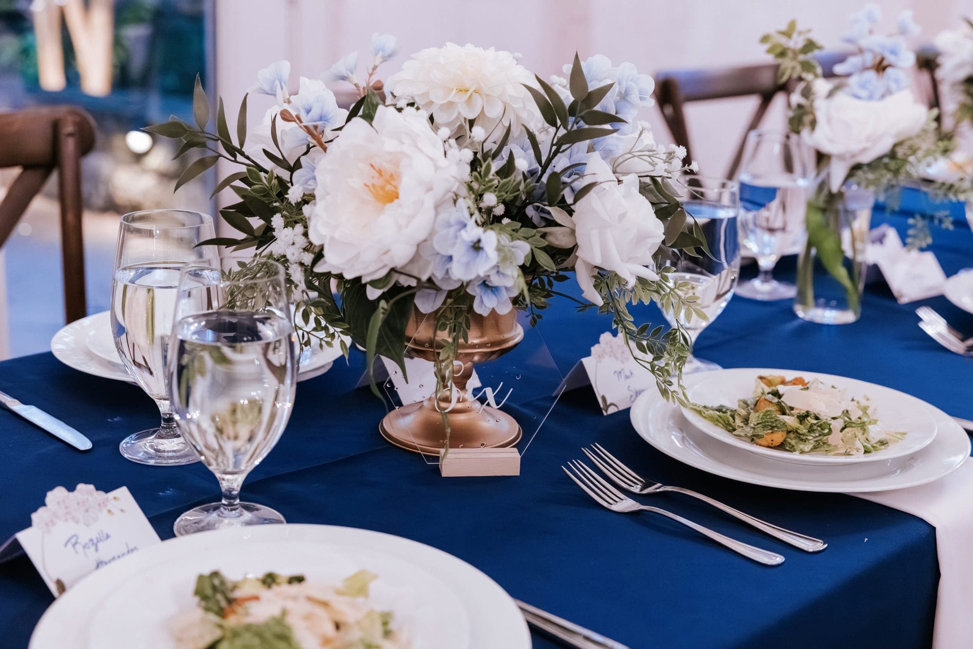 Place settings with acrylic name cards and plated salads on navy linen