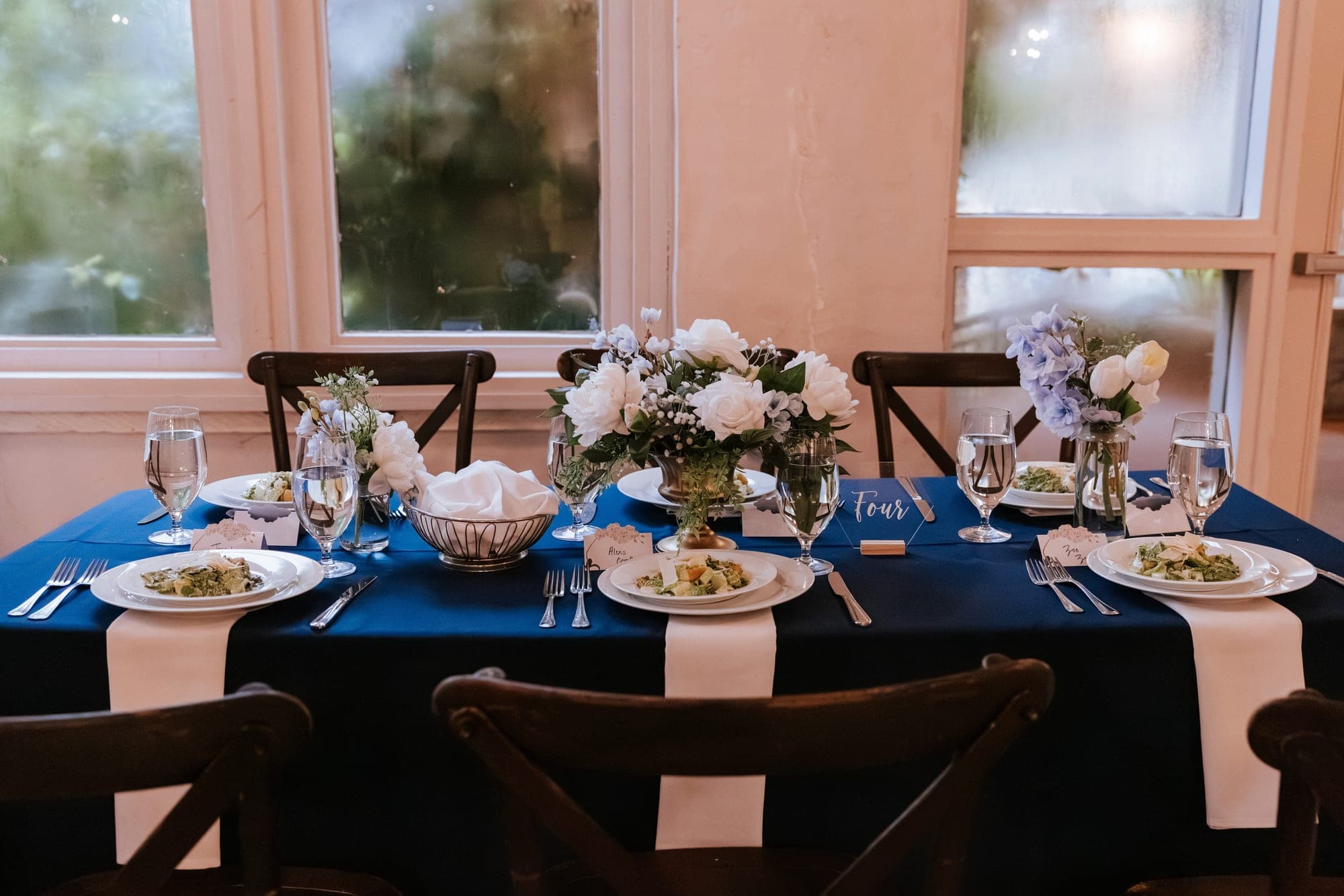The head table in the villa's bay window, navy linen and white and blue florals