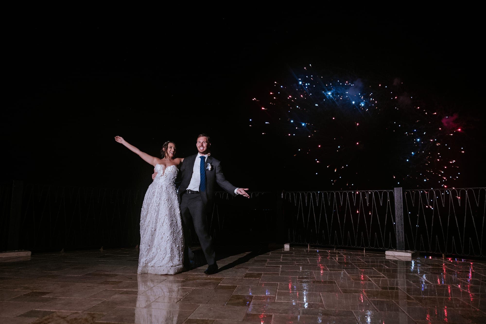 The couple on the wet terrace at night with fireworks rising in the distance