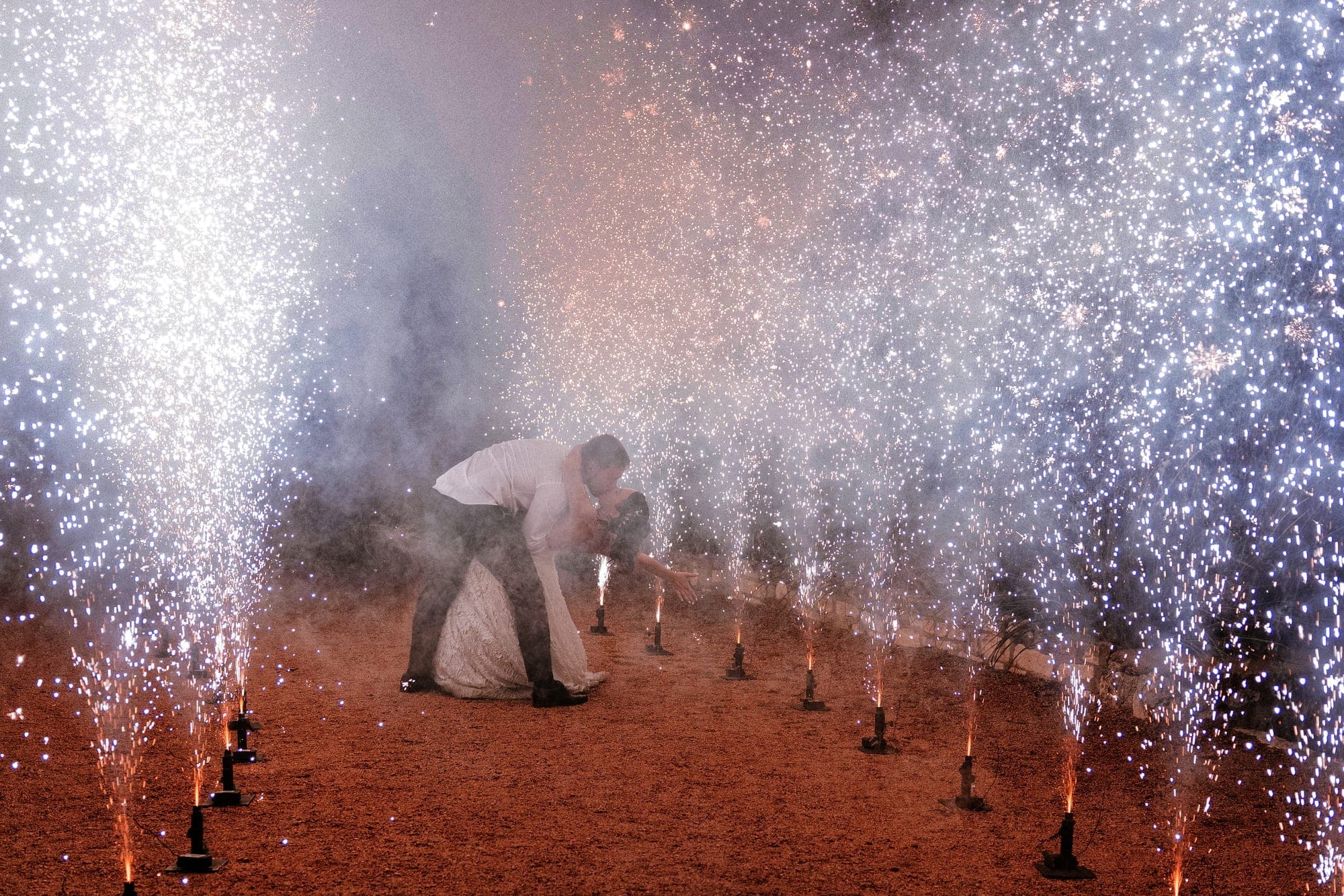 A final dip kiss inside a tunnel of cold-spark fountains
