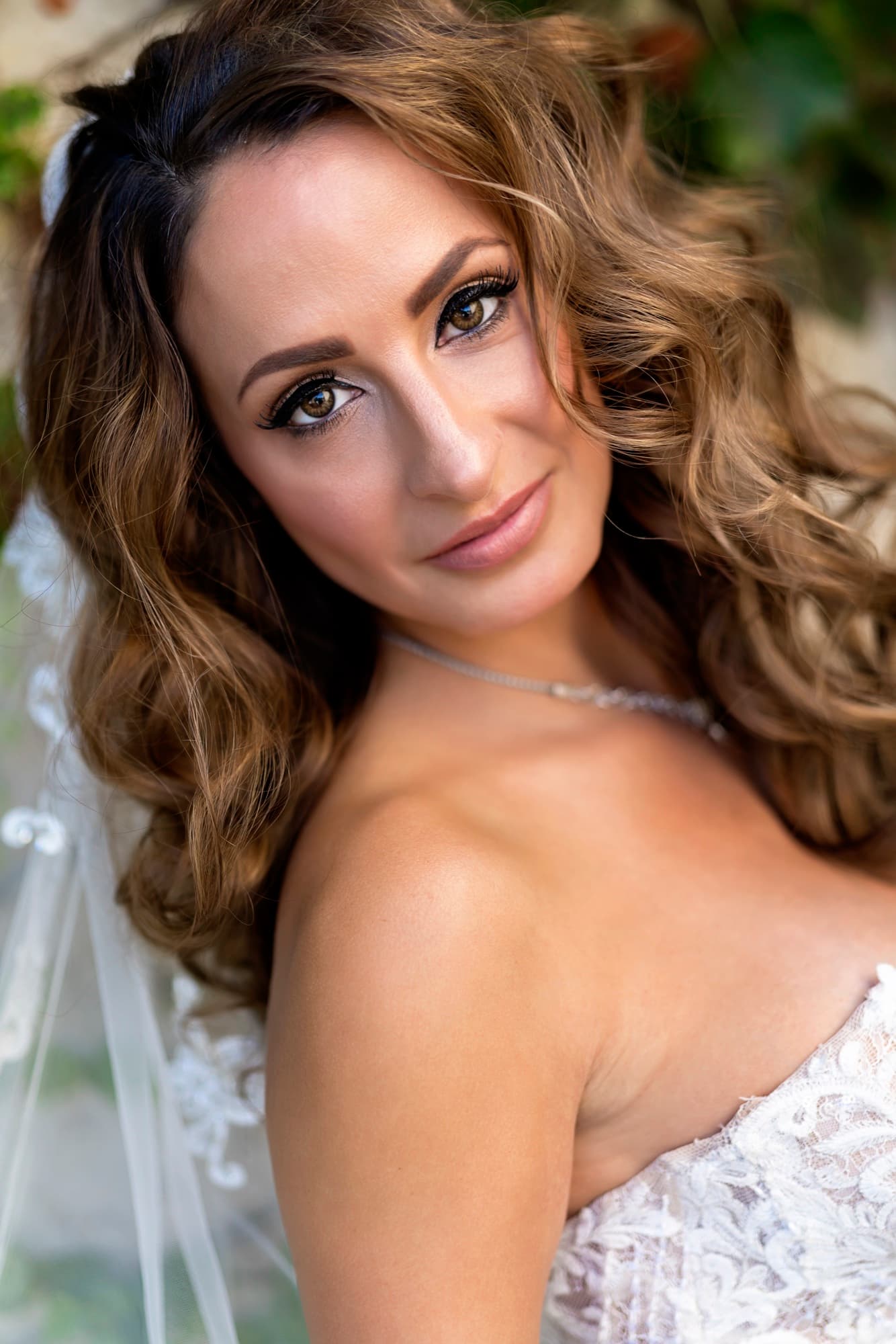 Editorial beauty portrait of Suzie with soft curls and a delicate necklace in the warm garden light at Disney Hall