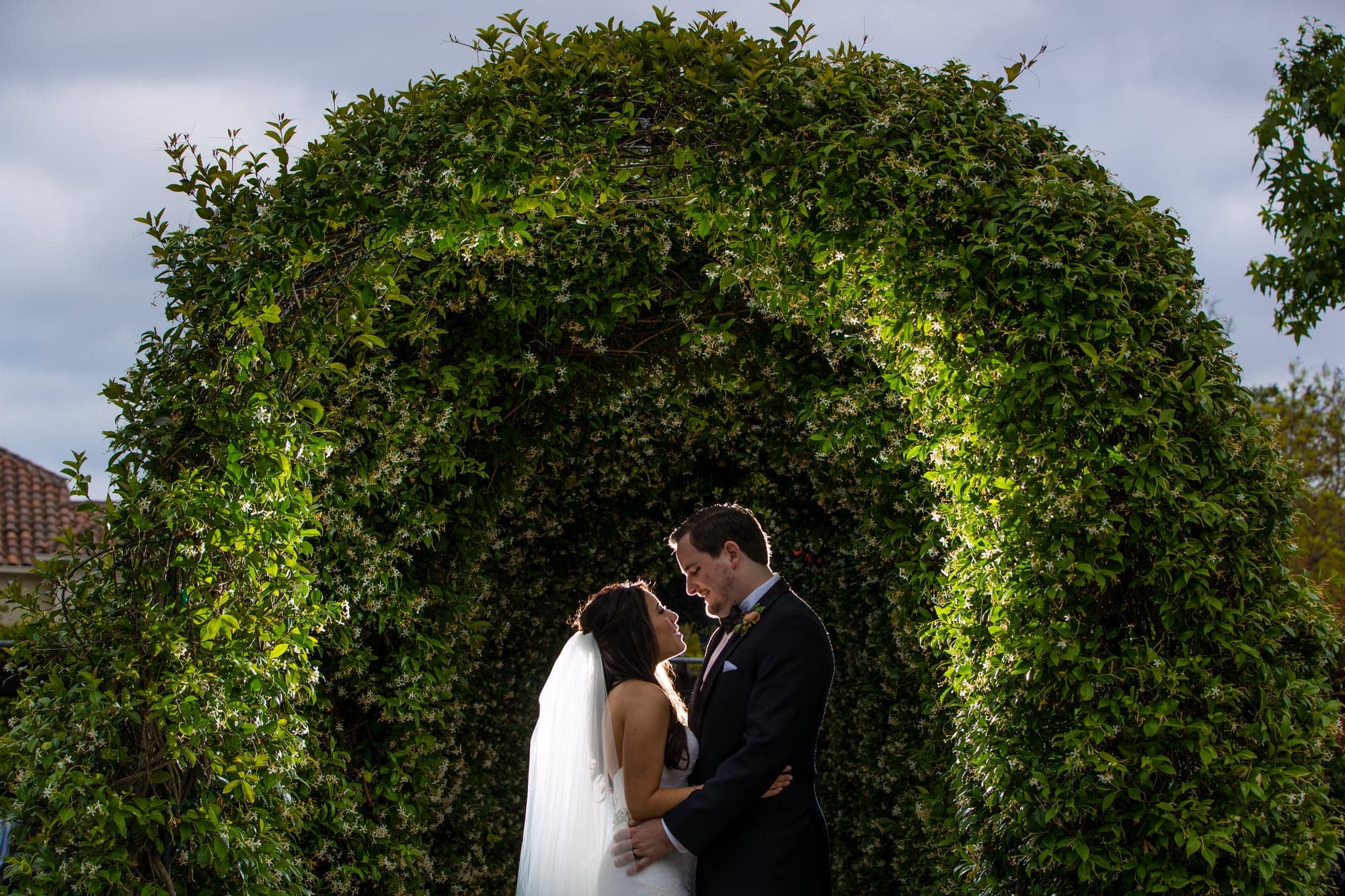 Brittany and Andrew beneath a green arch at Westlake Village Inn