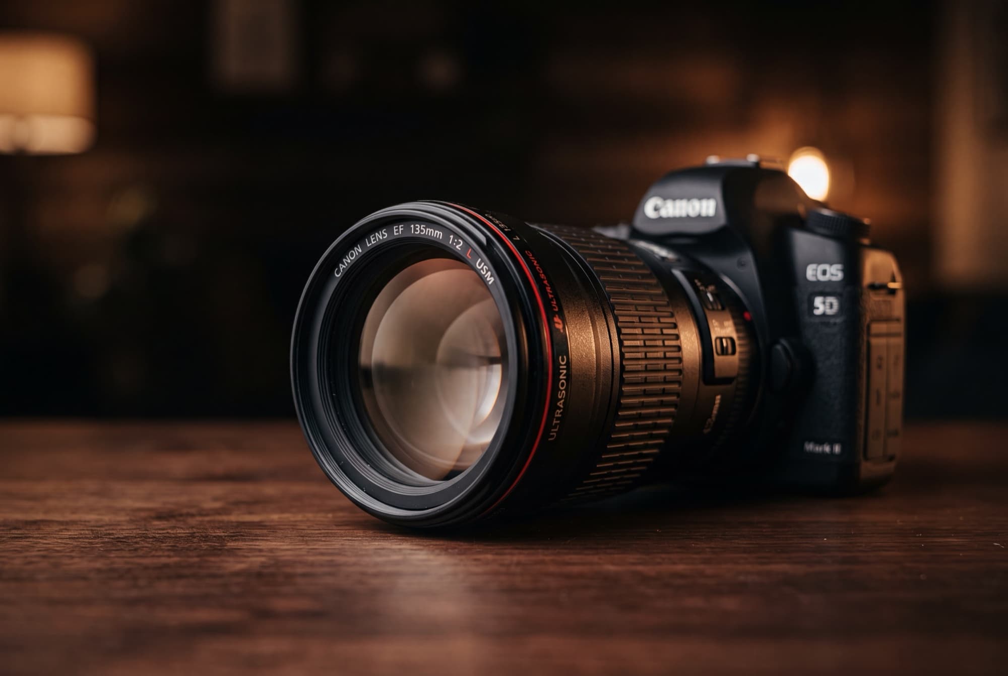 The Canon EF 135mm f/2L USM telephoto prime lens mounted on a Canon EOS 5D Mark II body, photographed in moody low light on a dark wood table