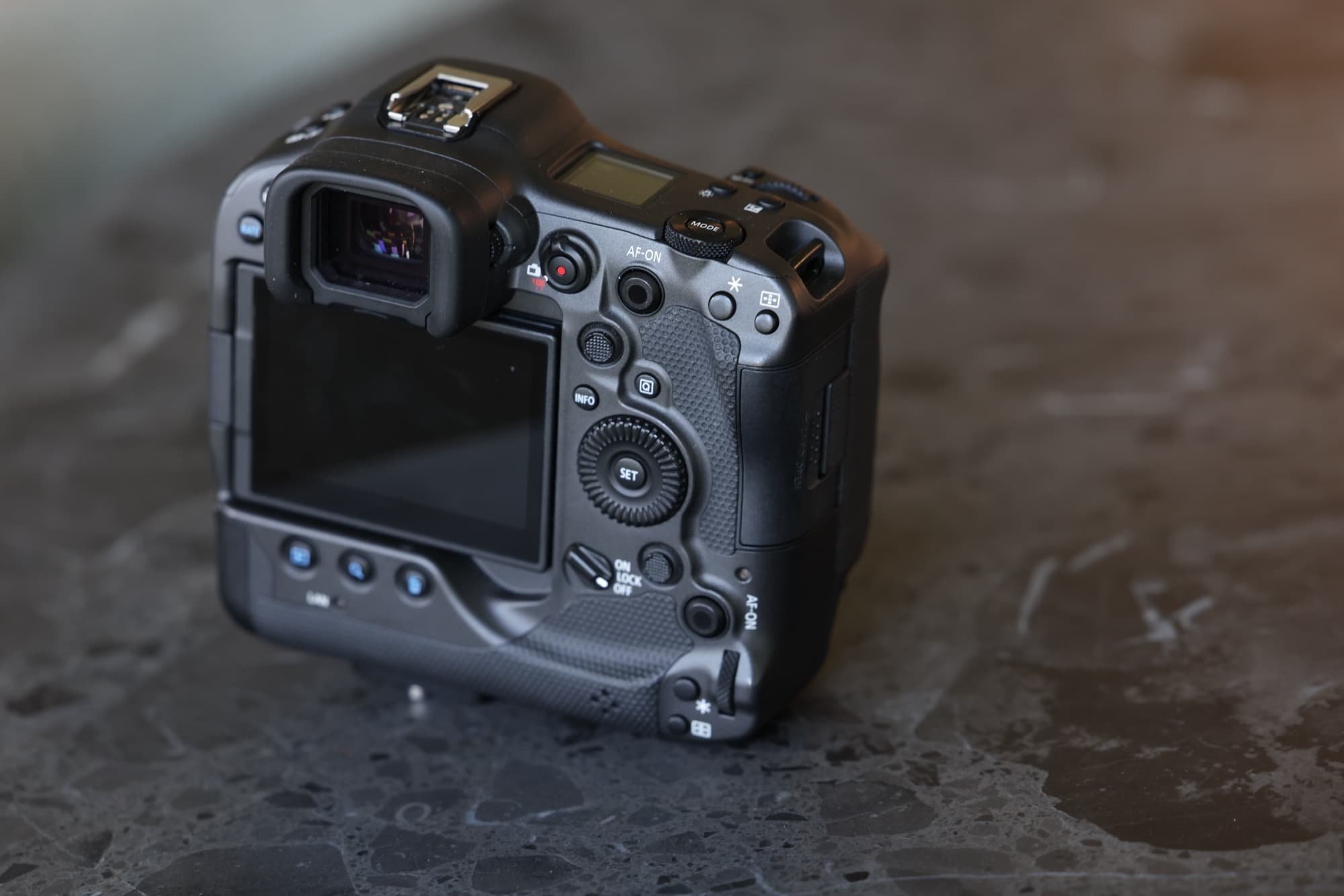 The back of the author's Canon EOS R3 showing the LCD, smart controller, and AF-ON button, photographed on a dark marble counter