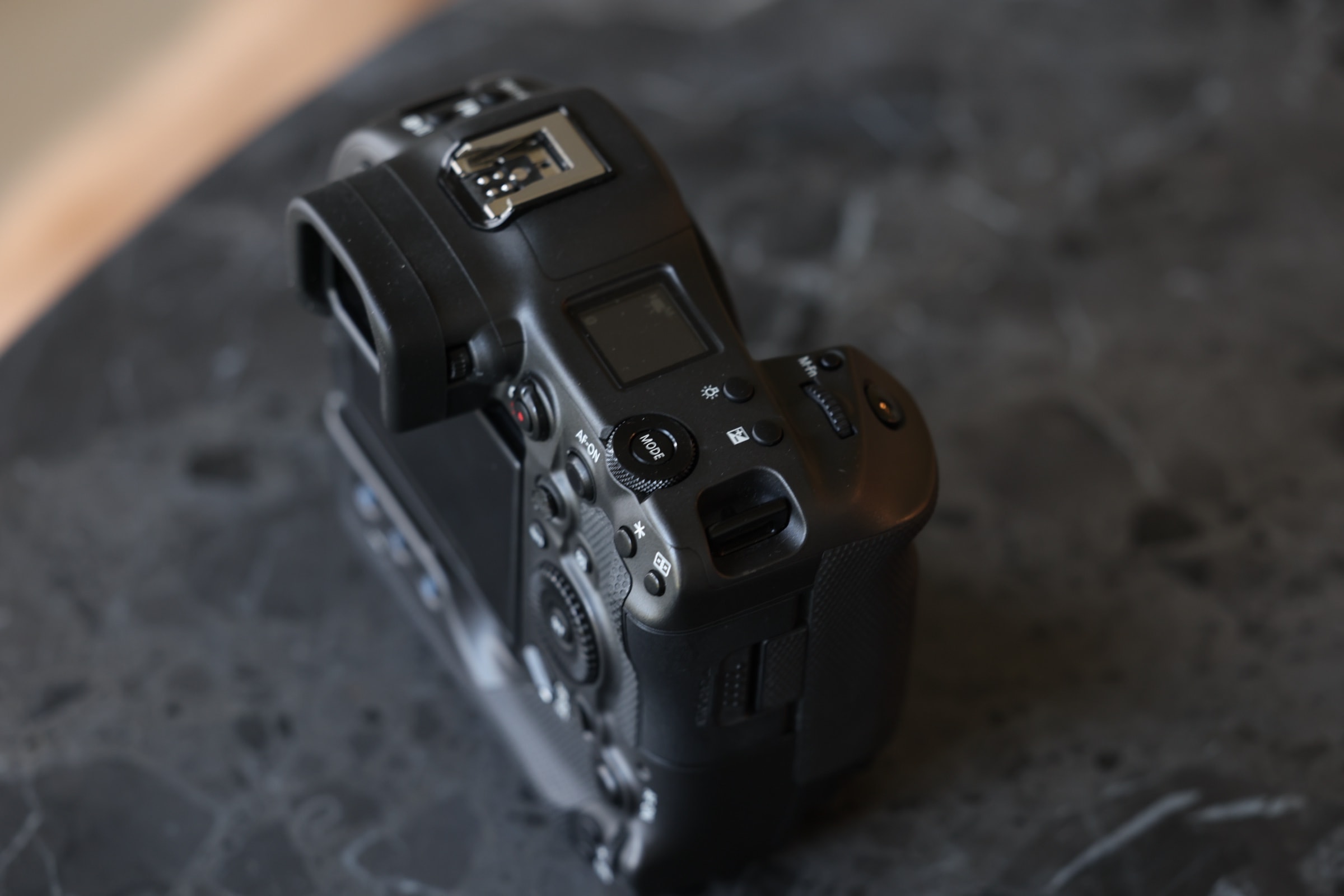 Top view of Michael Anthony's own Canon EOS R3 camera body on a dark marble counter in window light