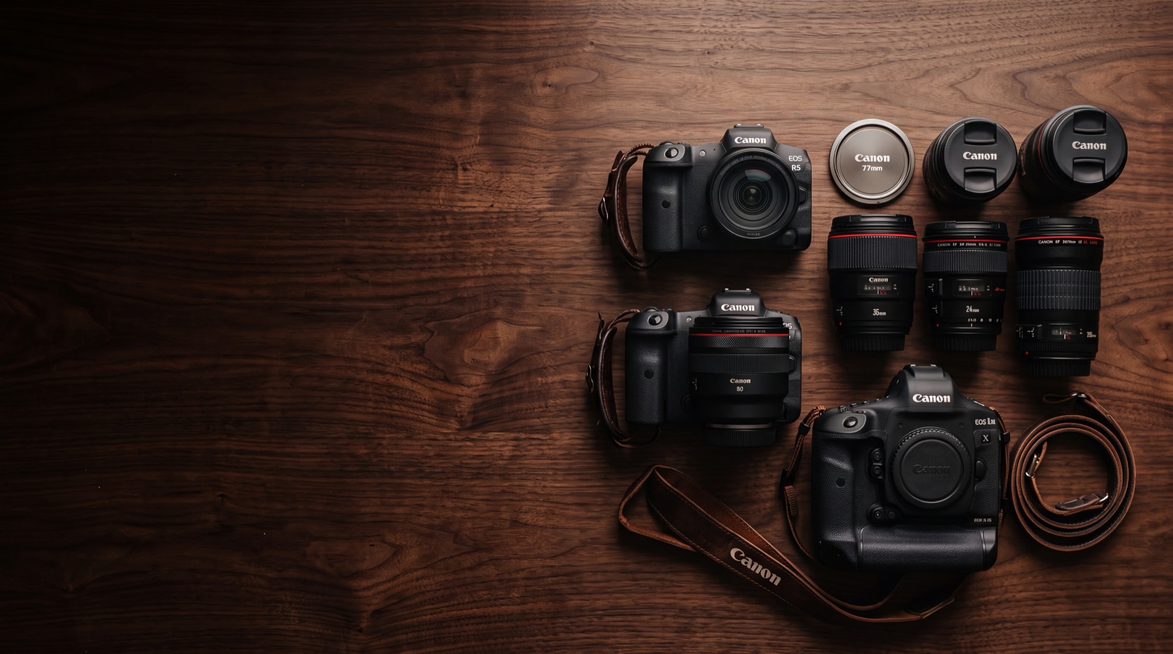 Professional wedding photographer's Canon camera bodies and L-series prime lenses arranged on a dark wood table