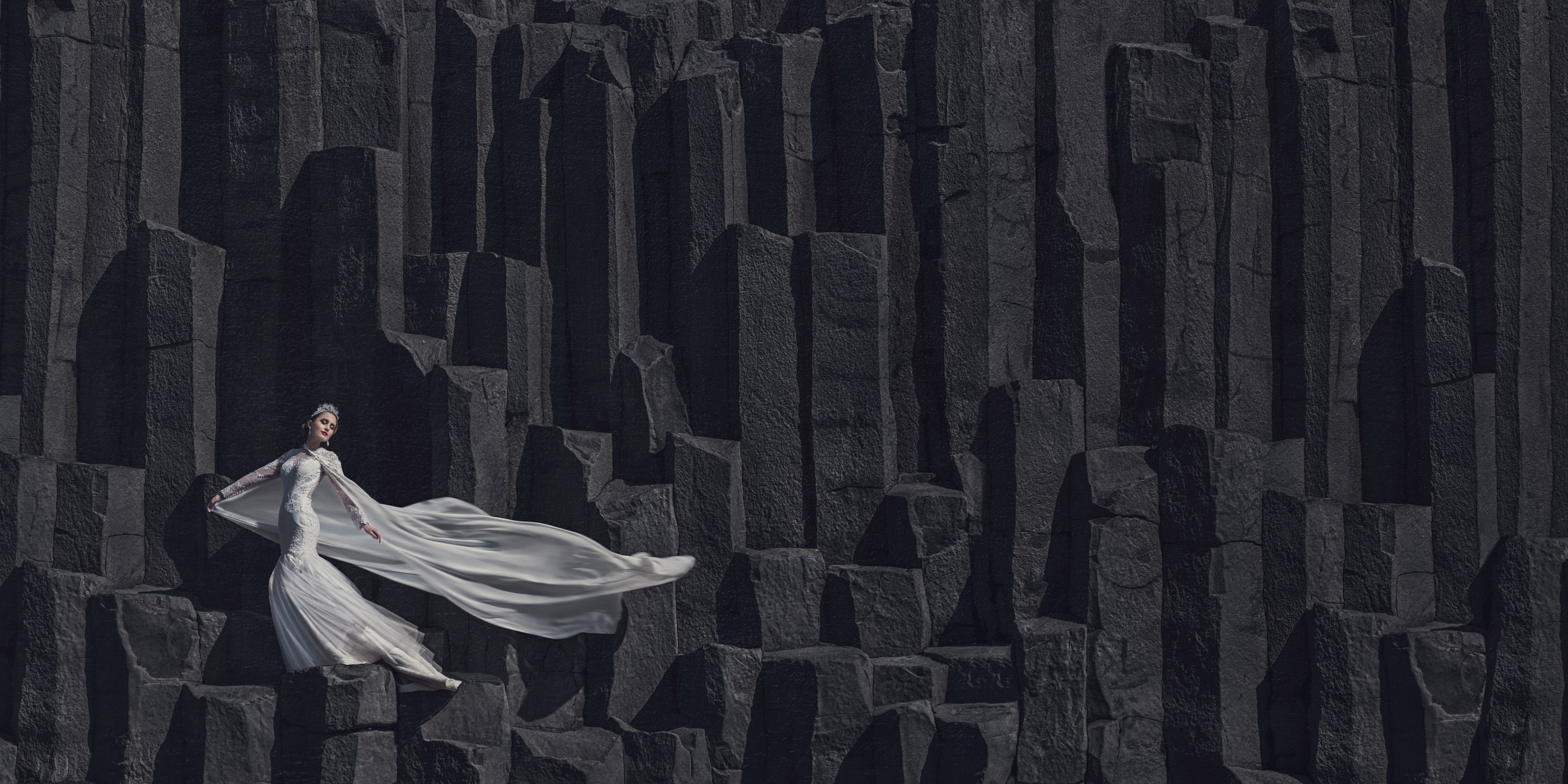 A bride in a flowing gown against the basalt columns in Iceland