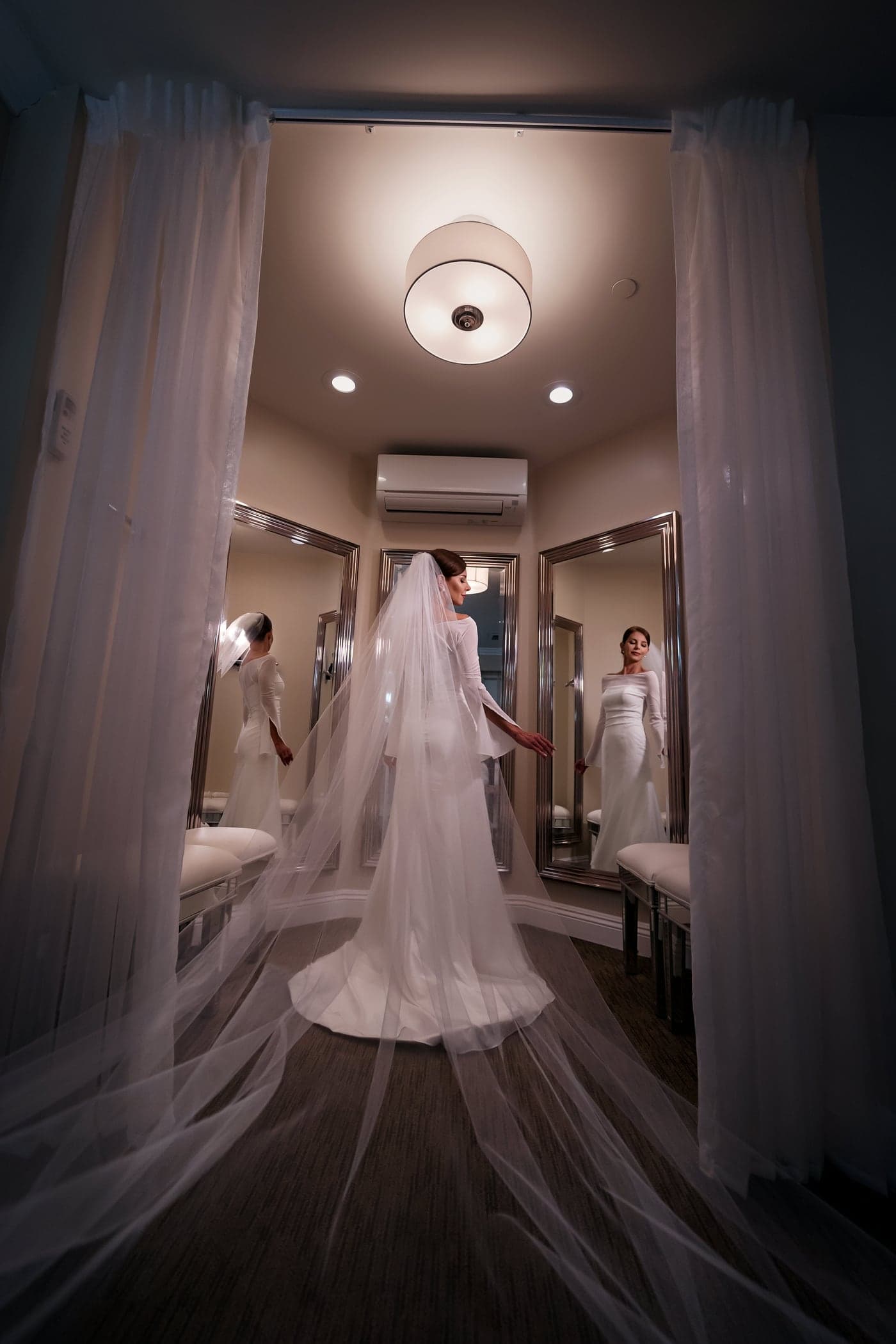 Bride in her cathedral veil among the mirrors of the bridal suite at Los Verdes Golf Course