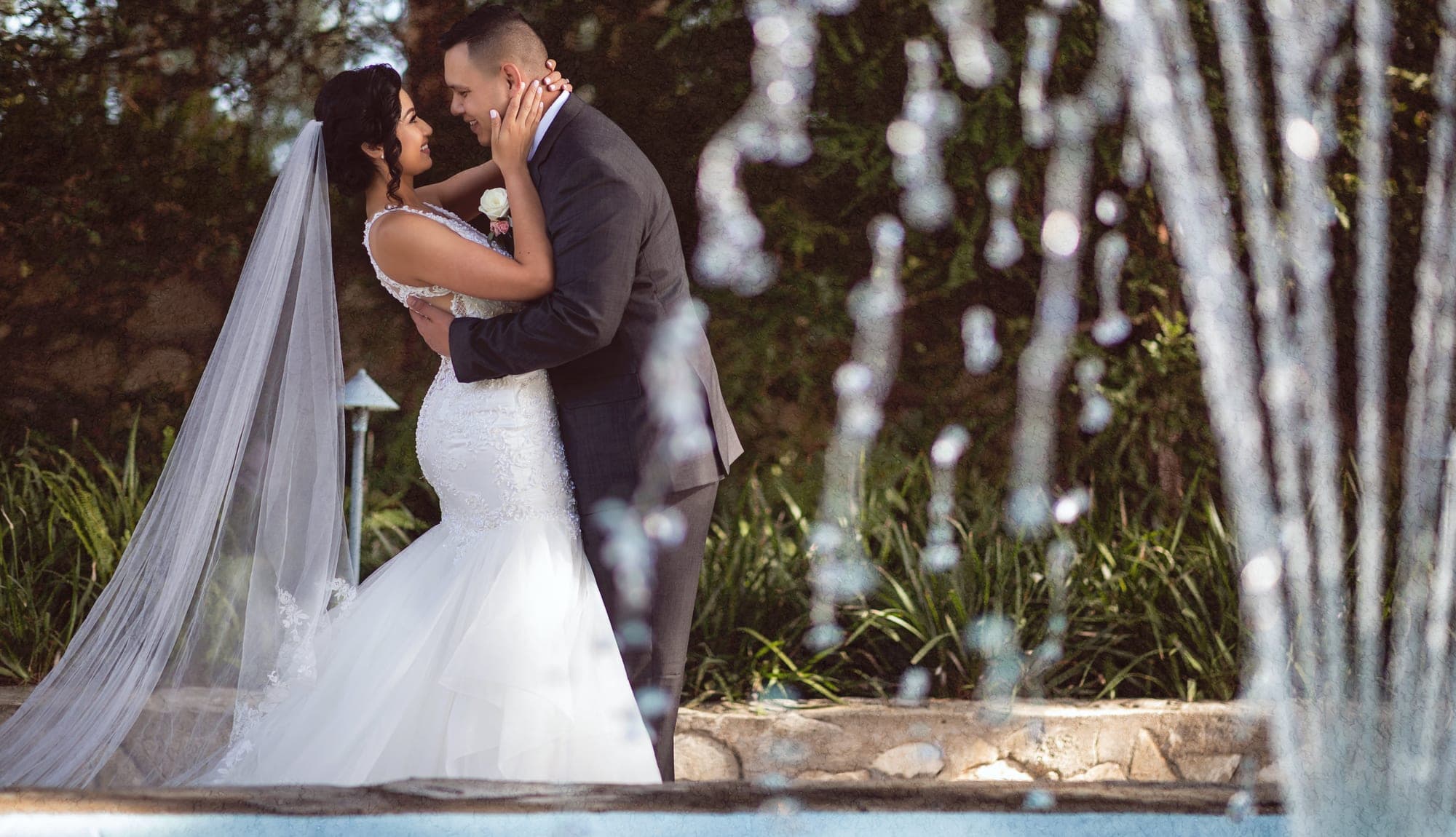 Bride and groom beside a garden fountain in Rancho Palos Verdes