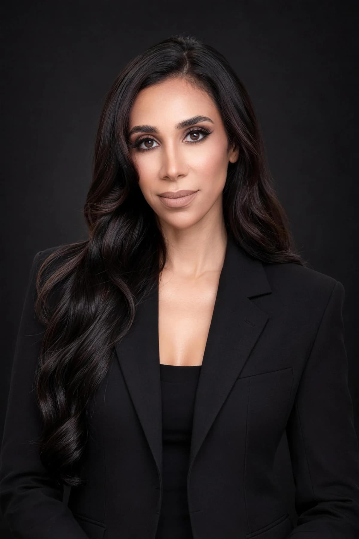 Jen in a black blazer against a dark studio backdrop
